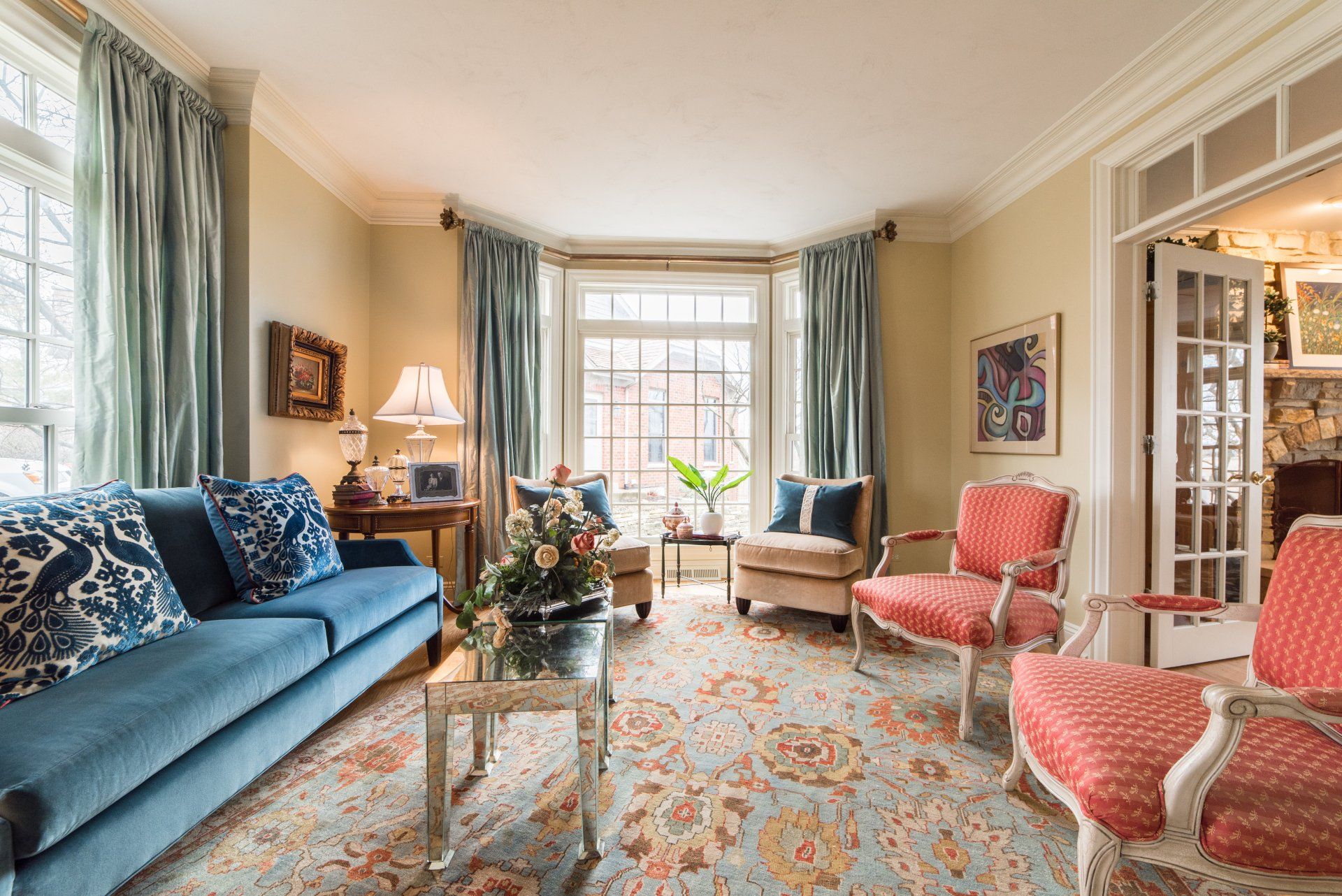 A living room with a blue couch , two chairs , a coffee table and a rug.
