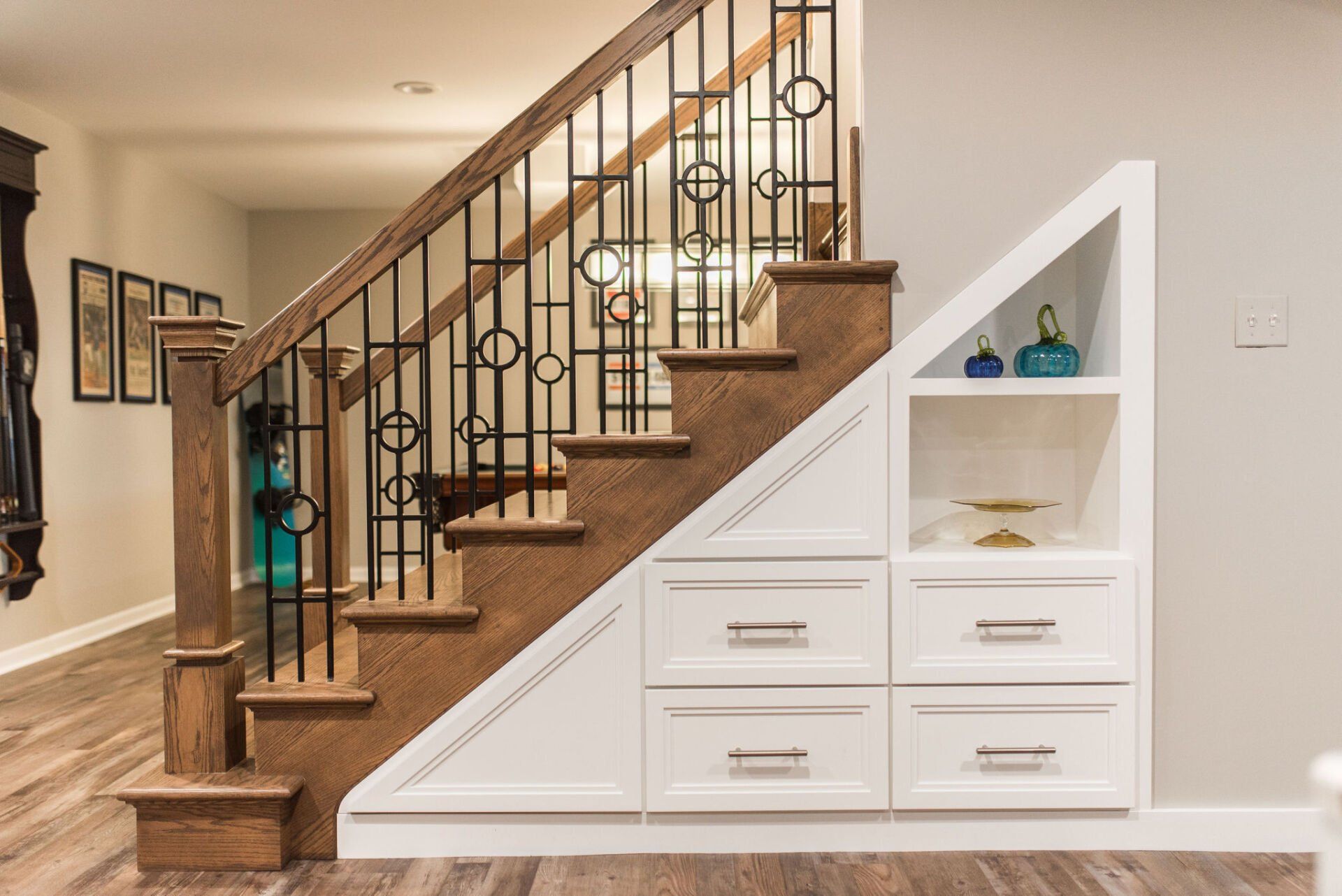 A staircase with a wrought iron railing and drawers underneath it.