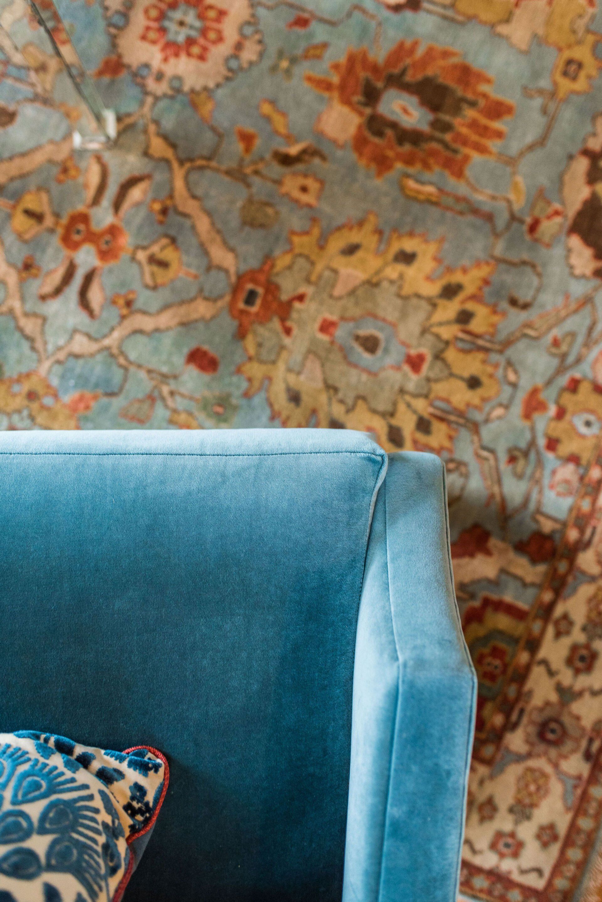 A blue chair is sitting in front of a rug.