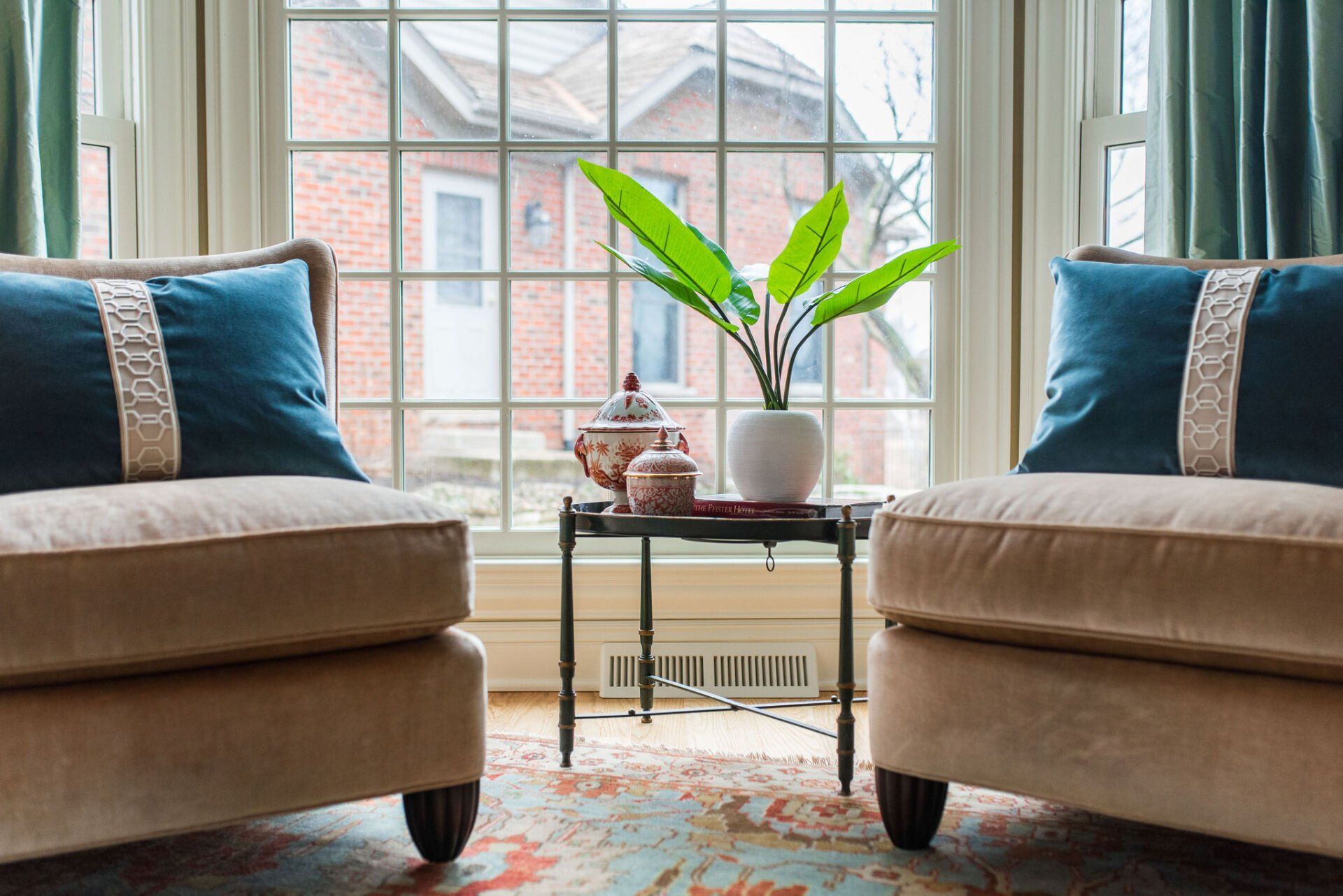 A living room with two chairs and a plant in front of a window.