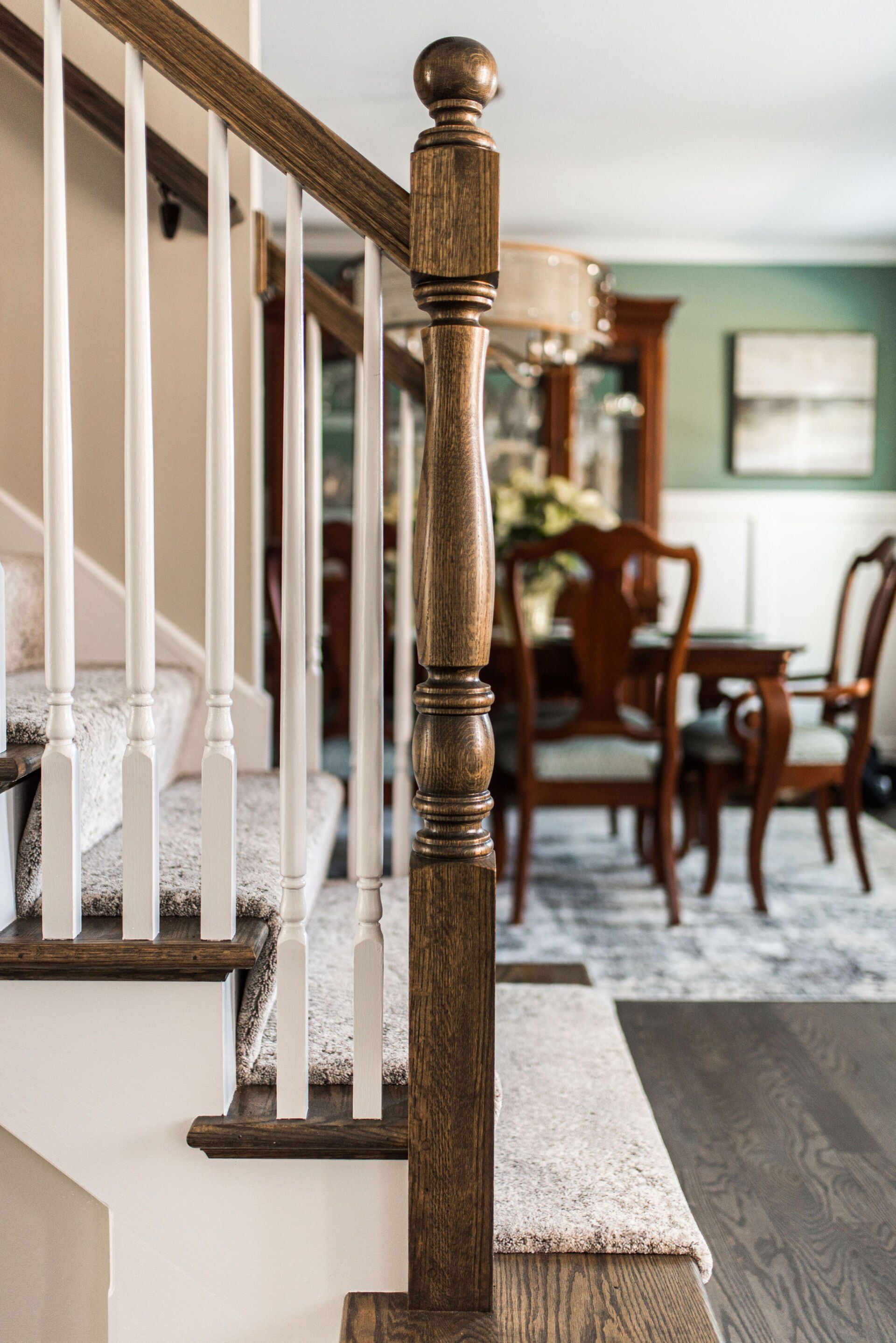 A close up of a staircase in a house with a dining room in the background.