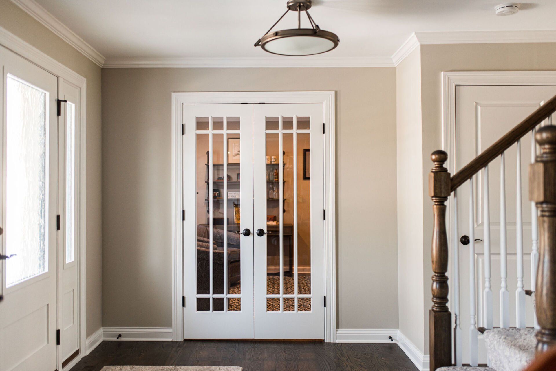 A hallway with french doors and a staircase in a house.