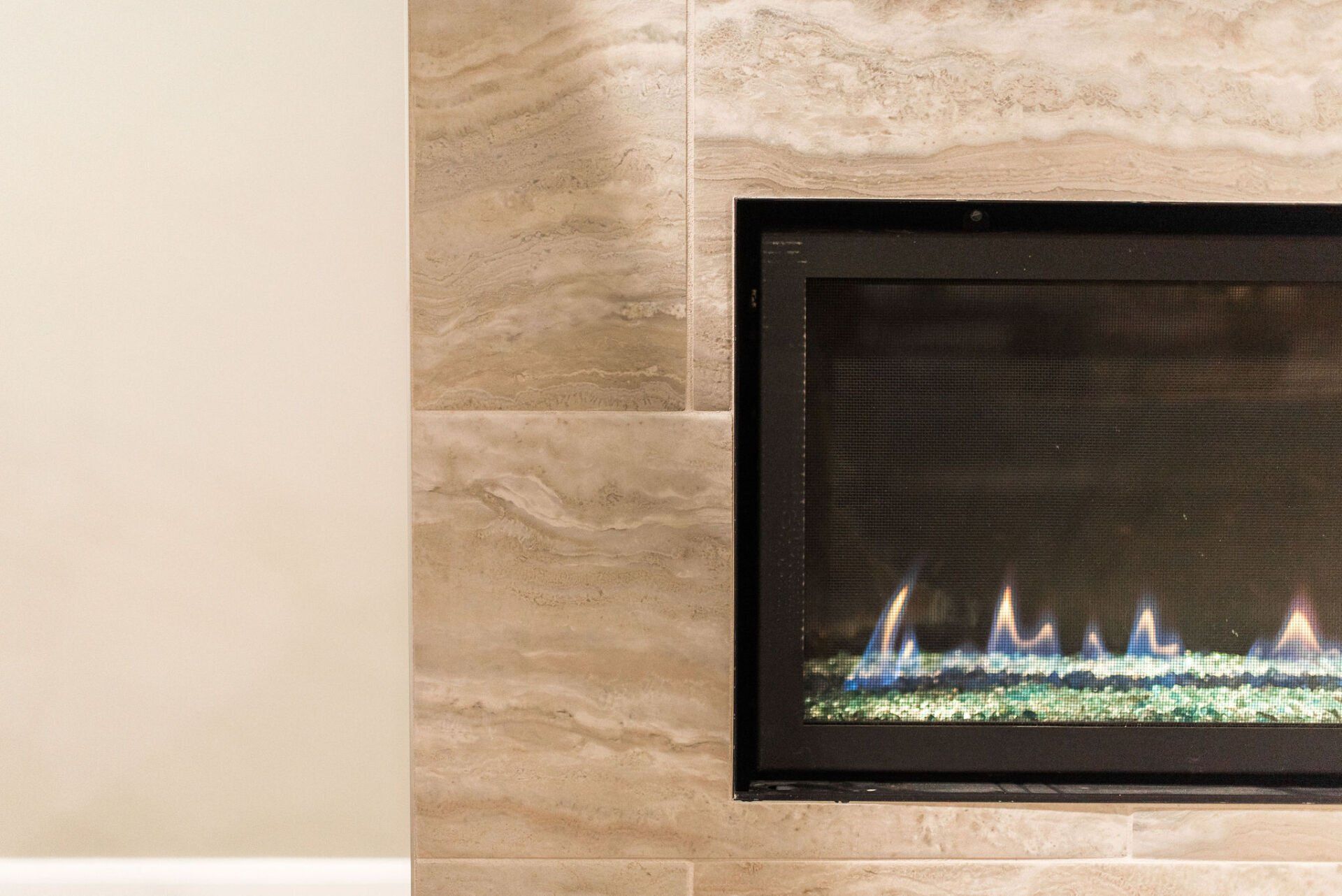 A fireplace is sitting on a tiled wall in a living room.