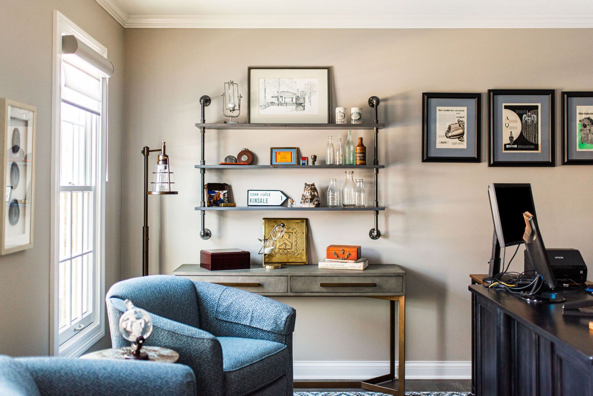 A living room with a desk , chair , and shelves.
