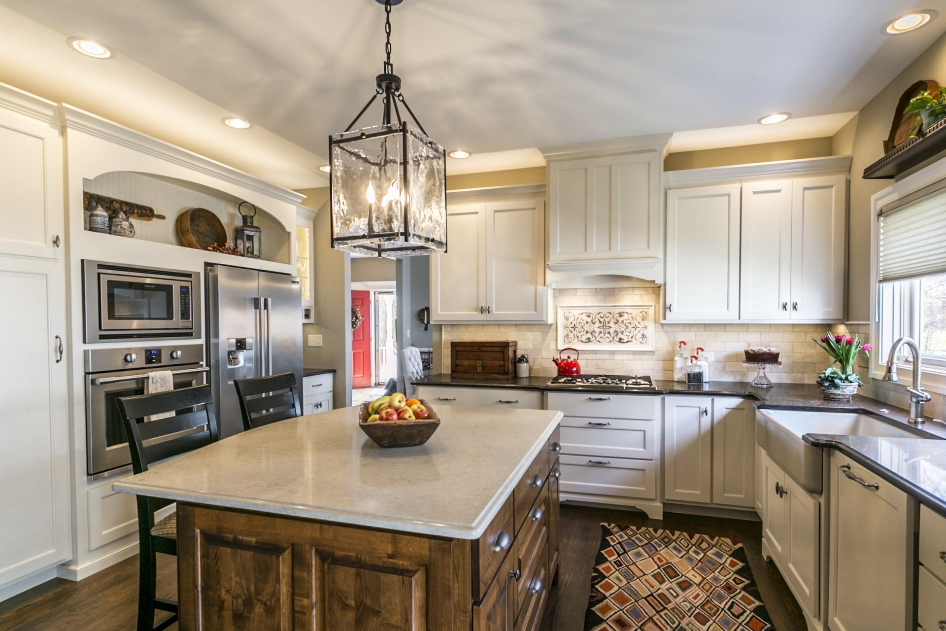 A kitchen with white cabinets and stainless steel appliances and a large island in the middle.