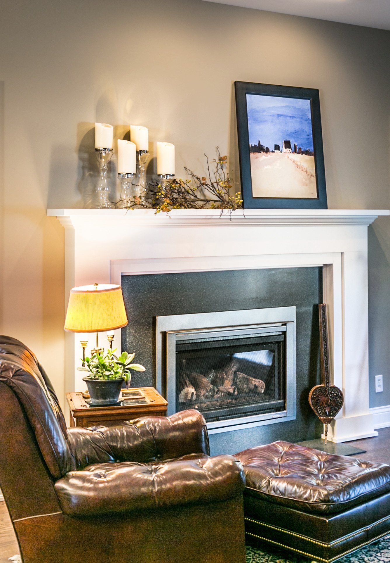 A living room with a fireplace , chair and ottoman