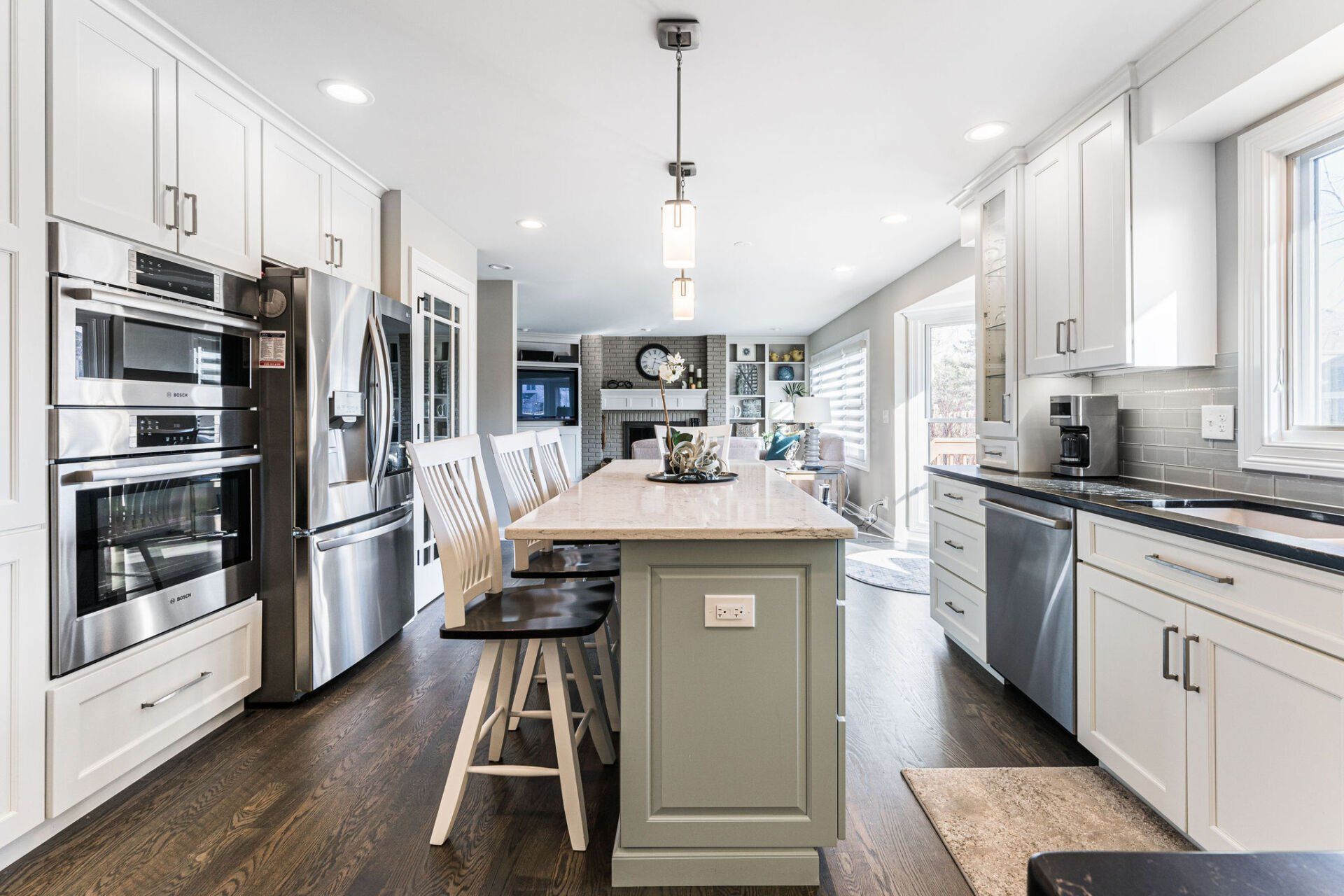 A kitchen with white cabinets , stainless steel appliances , and a large island.