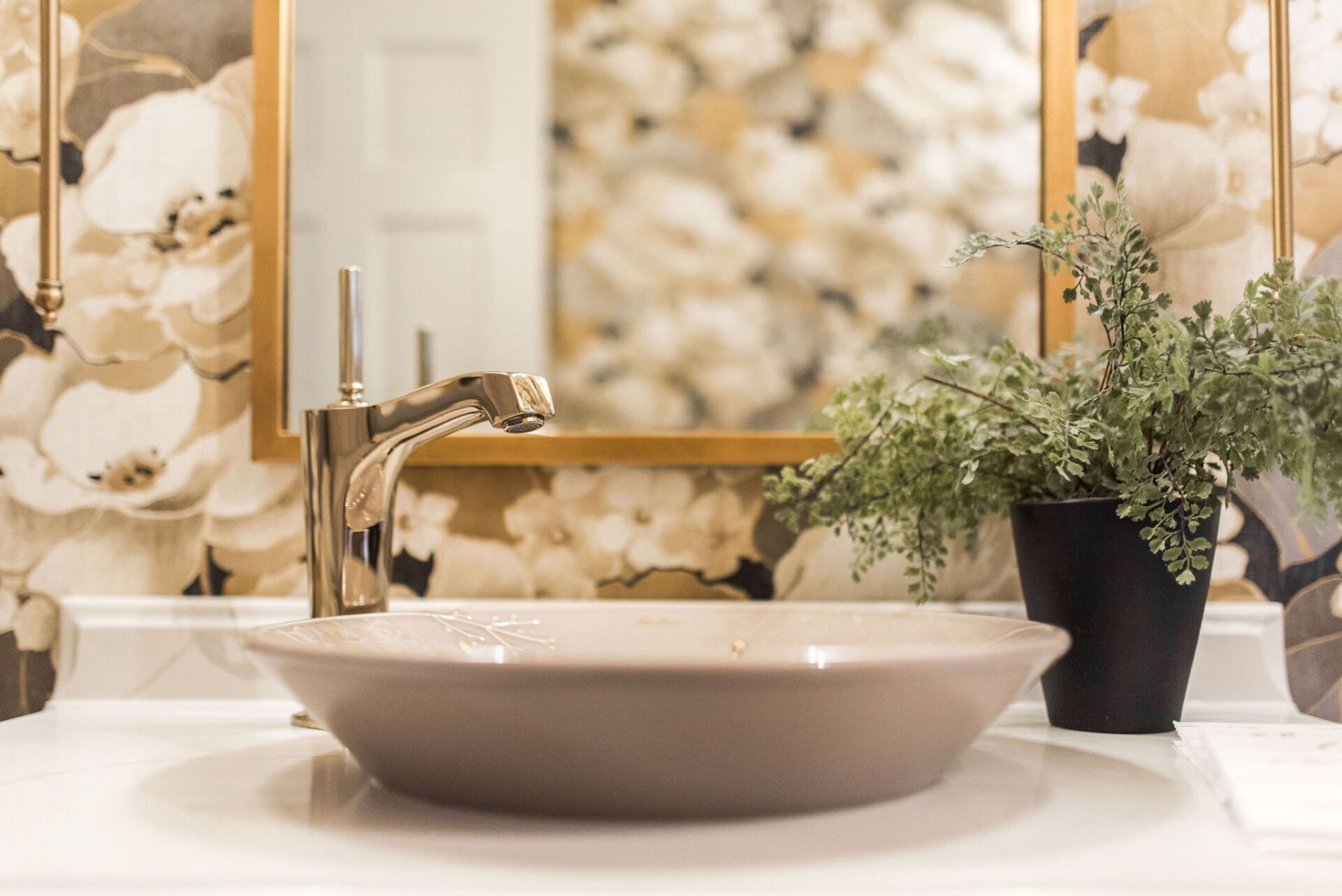 A bathroom sink with a potted plant next to it.