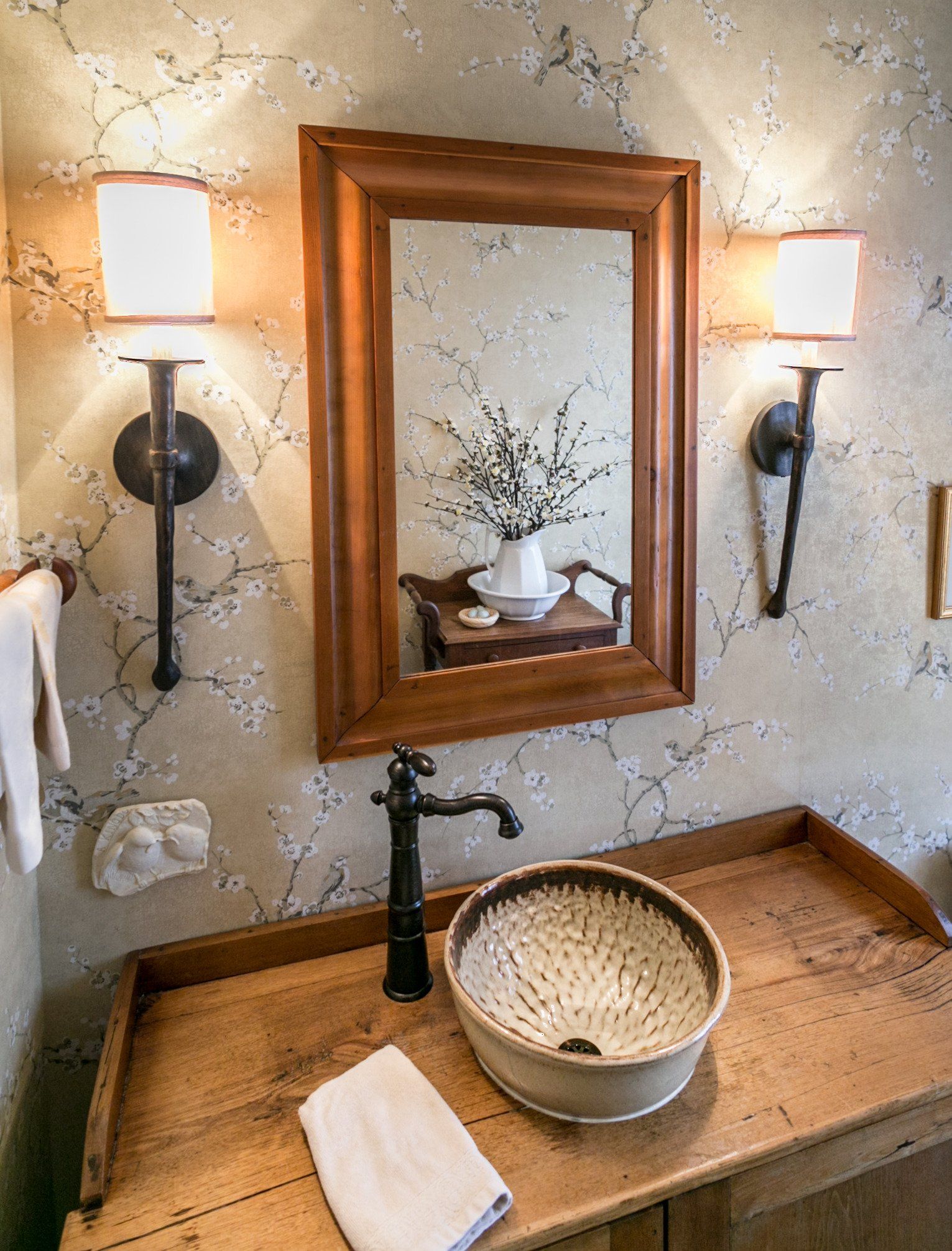 A bathroom with a sink , mirror and two lights.