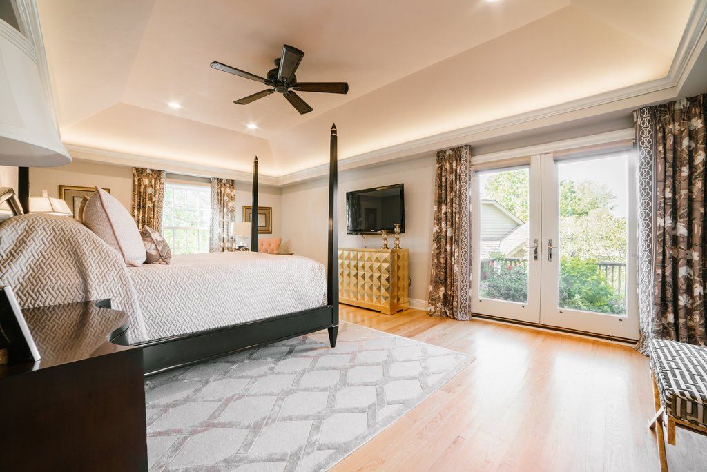A large bedroom with a four poster bed and a ceiling fan.
