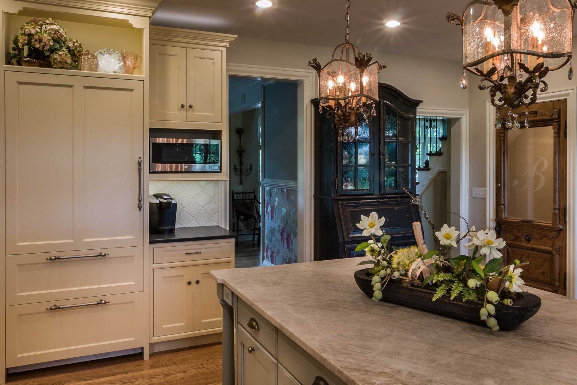 A kitchen with white cabinets and a large island with flowers on it.