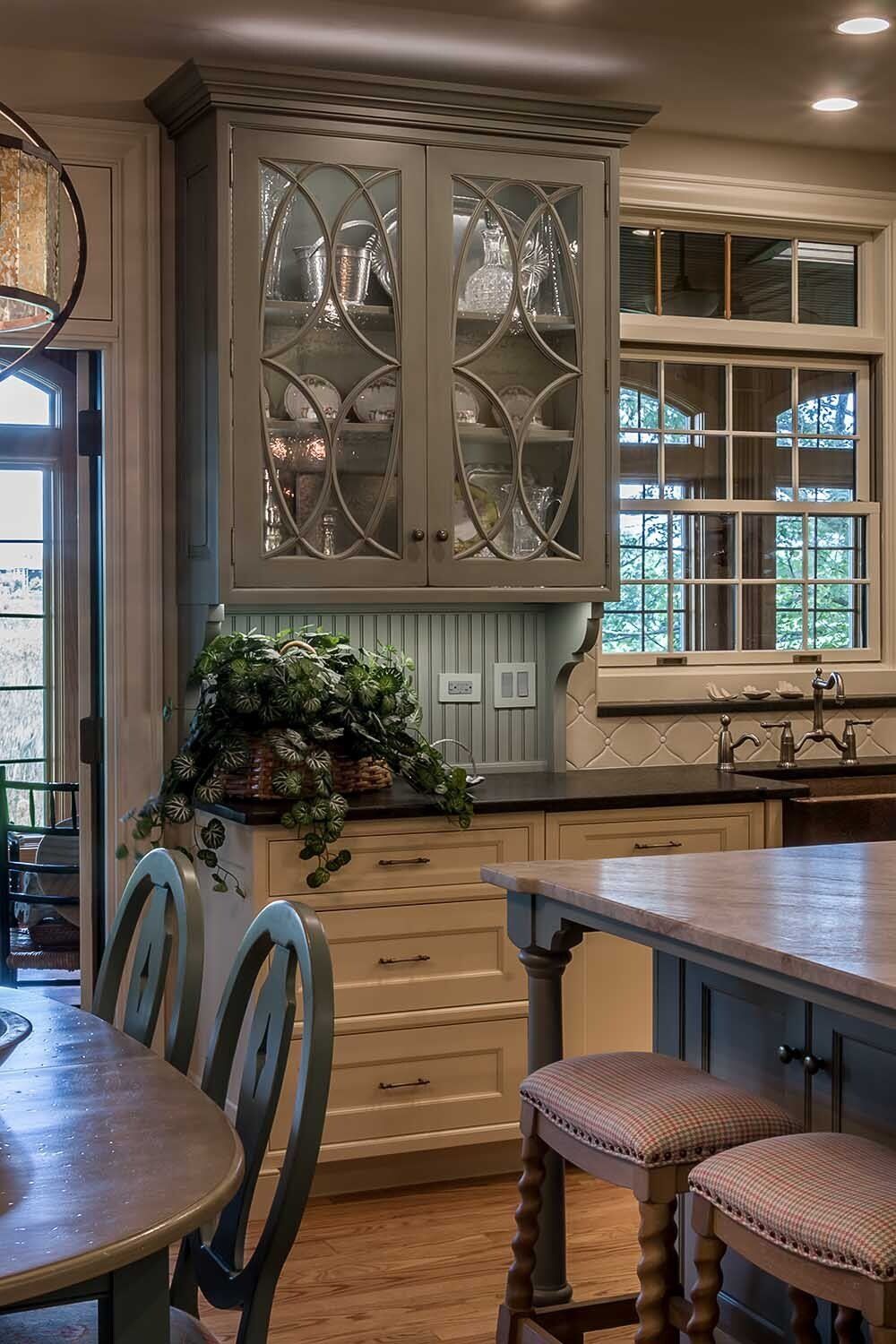 A kitchen with a table , chairs , cabinets and a sink.