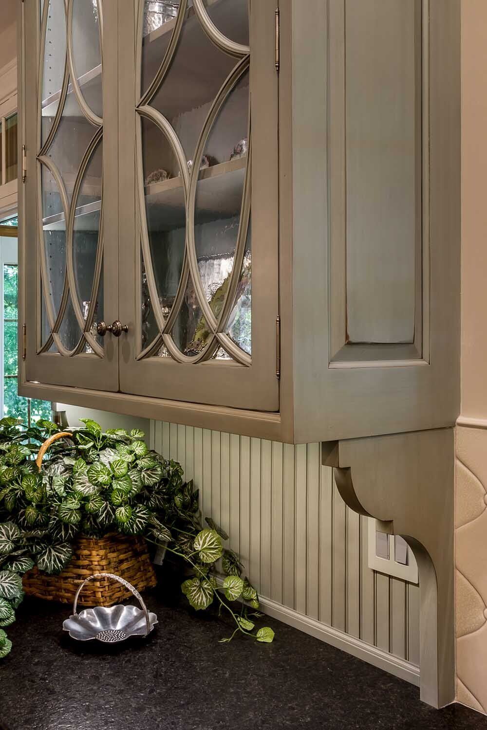 A kitchen cabinet with a glass door and a basket on the counter.