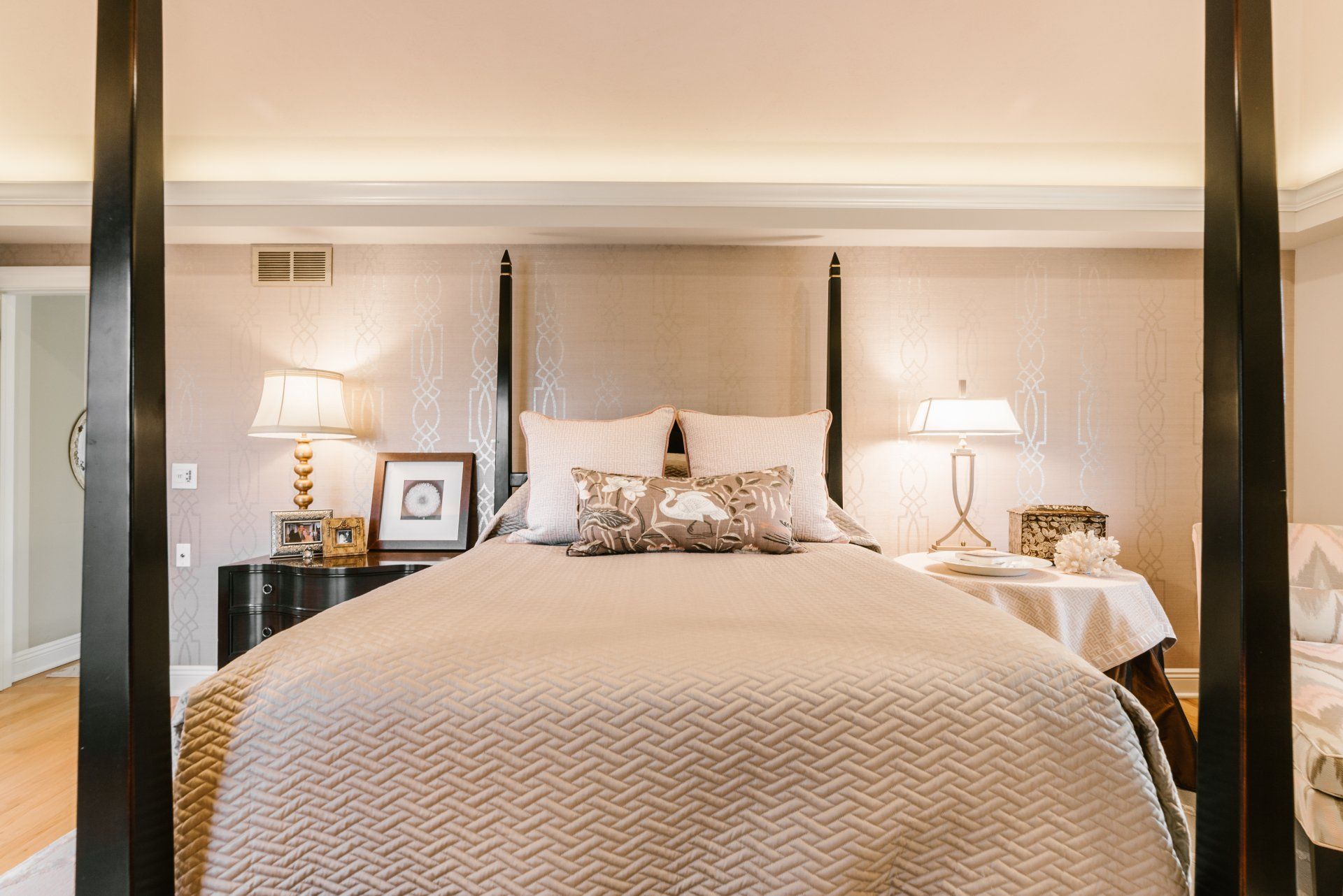 A bedroom with a four poster bed and lamps.
