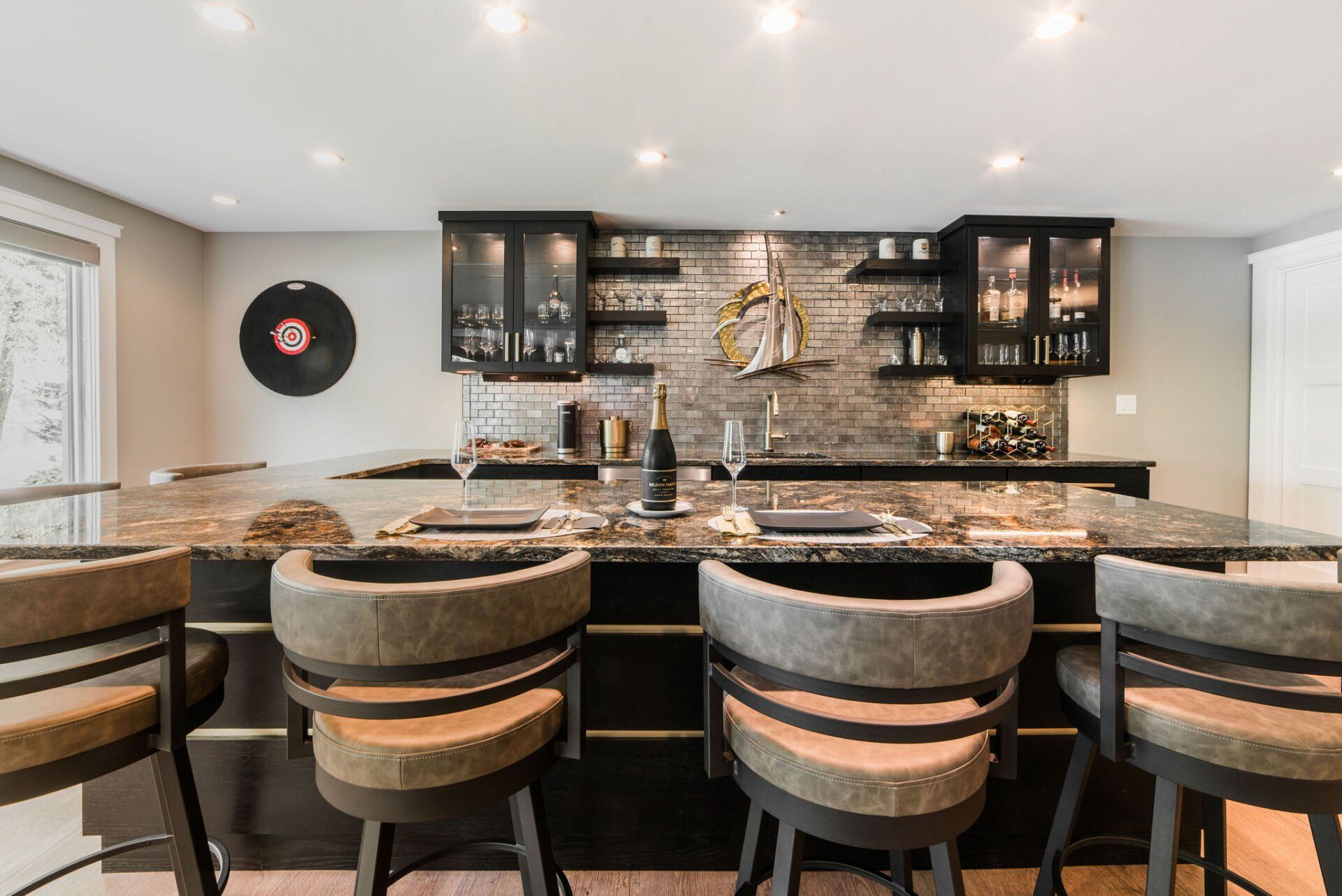 A kitchen with a bar and stools and a record on the wall.