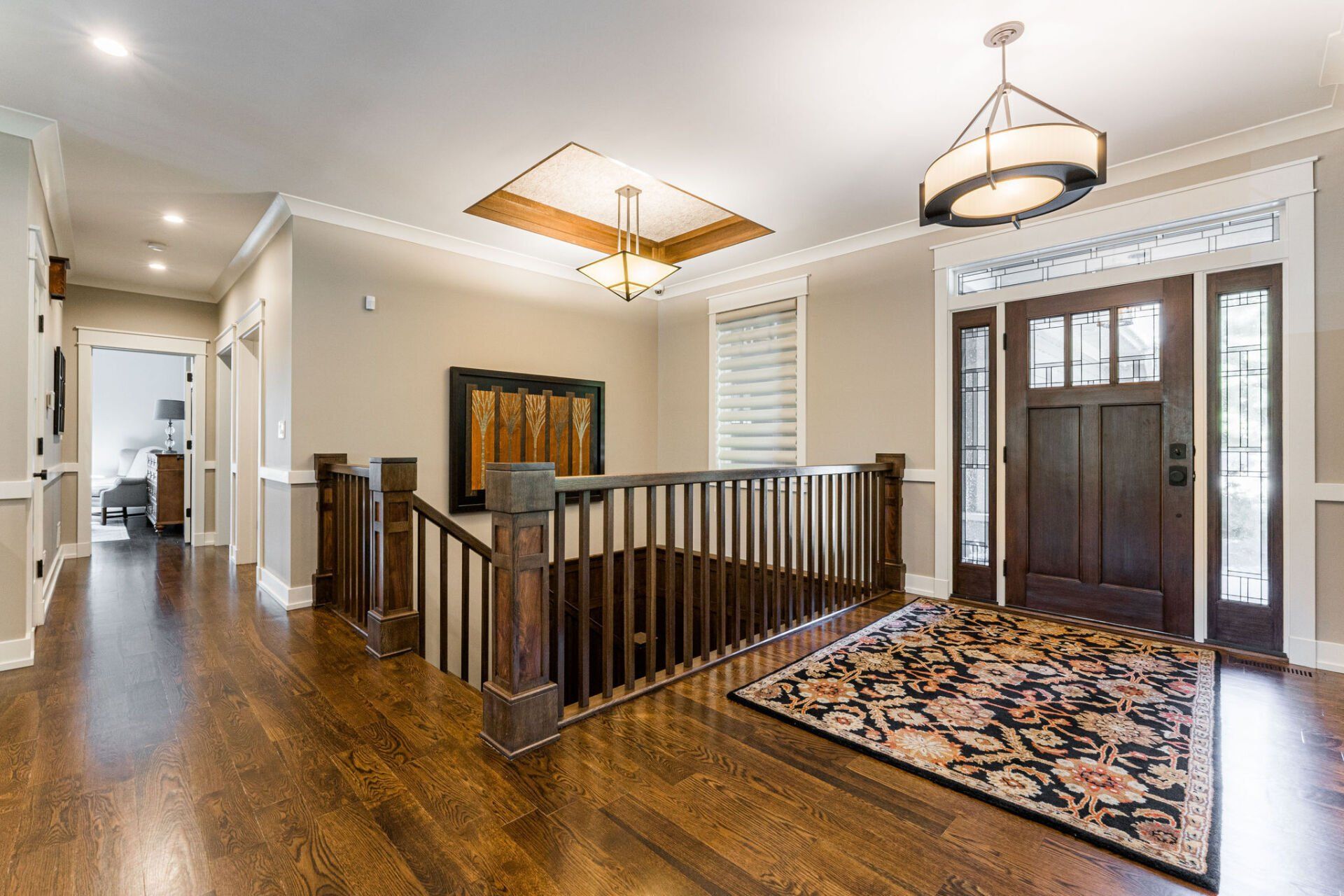 A large hallway with hardwood floors and a staircase in a house.