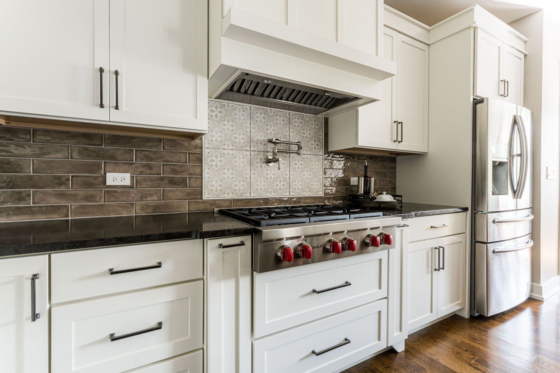 A kitchen with white cabinets , stainless steel appliances , a stove and a refrigerator.