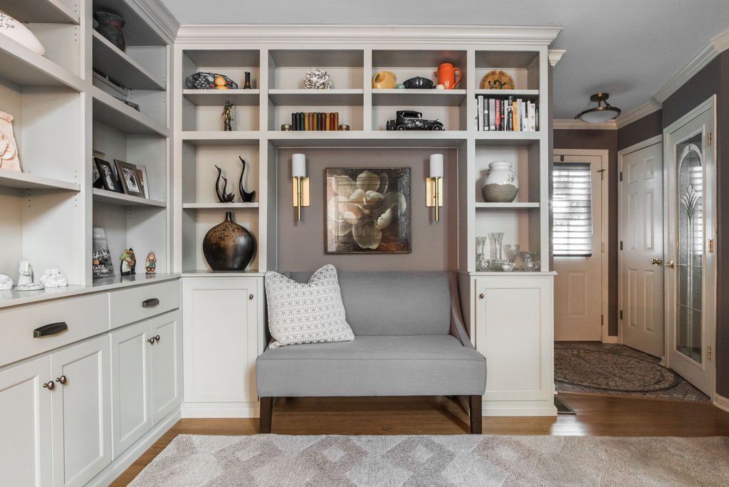 A living room with a couch , shelves , and a painting on the wall.