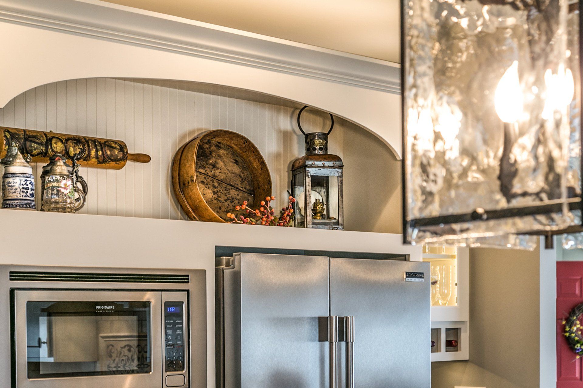 A kitchen with a stainless steel refrigerator , microwave , and chandelier.