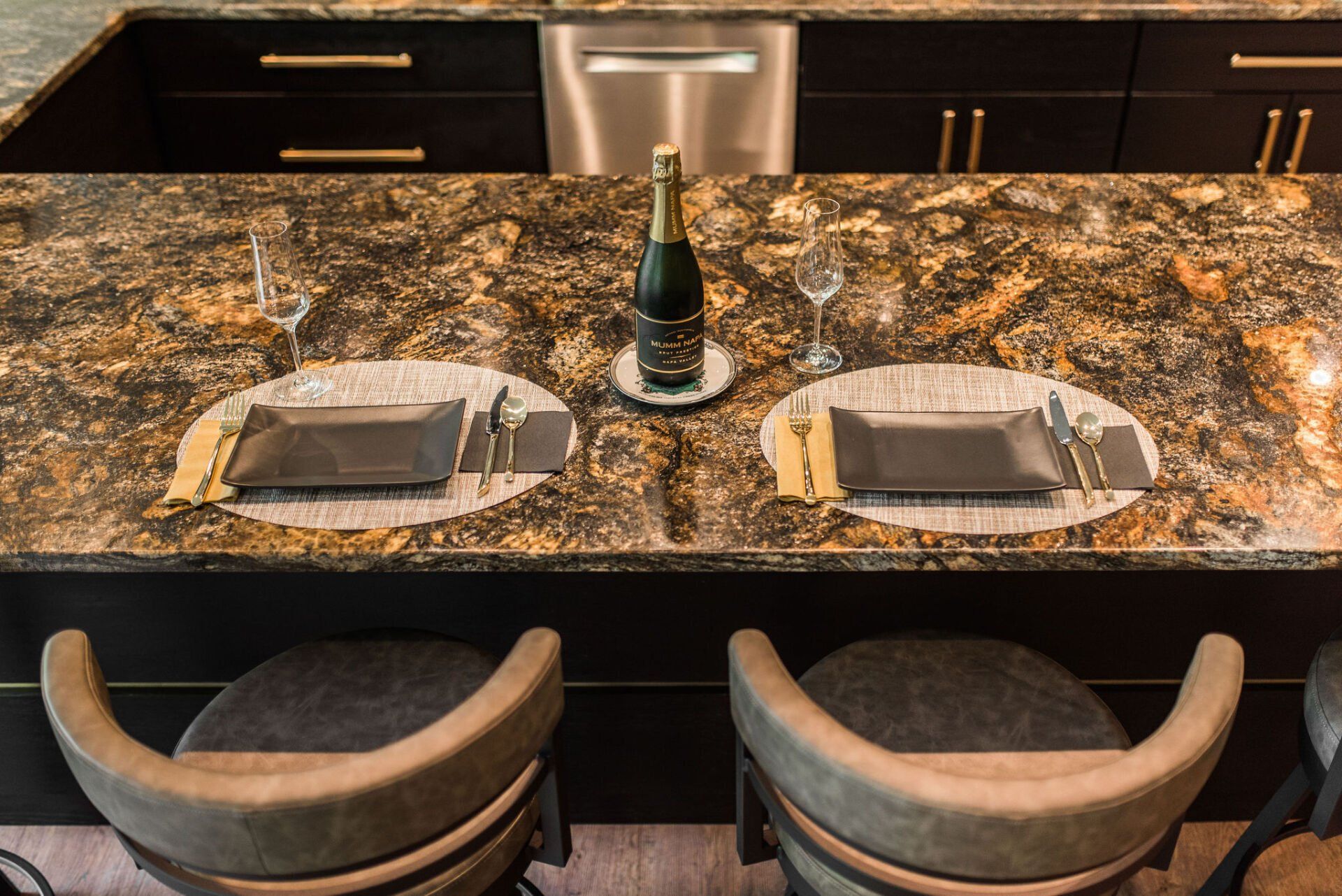 A kitchen counter with two chairs and a bottle of champagne on it.