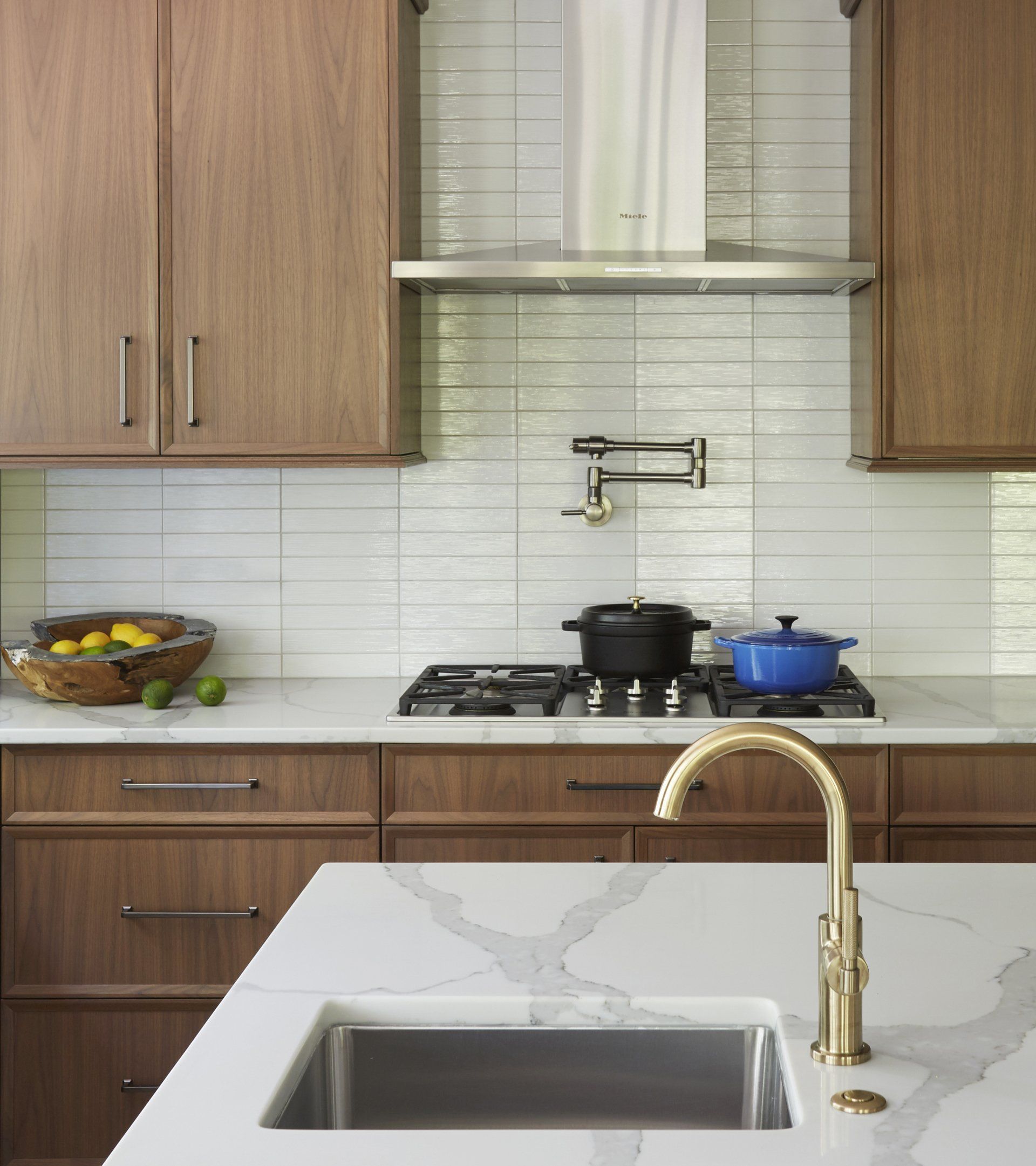 A kitchen with a sink , stove top oven , pots and pans.