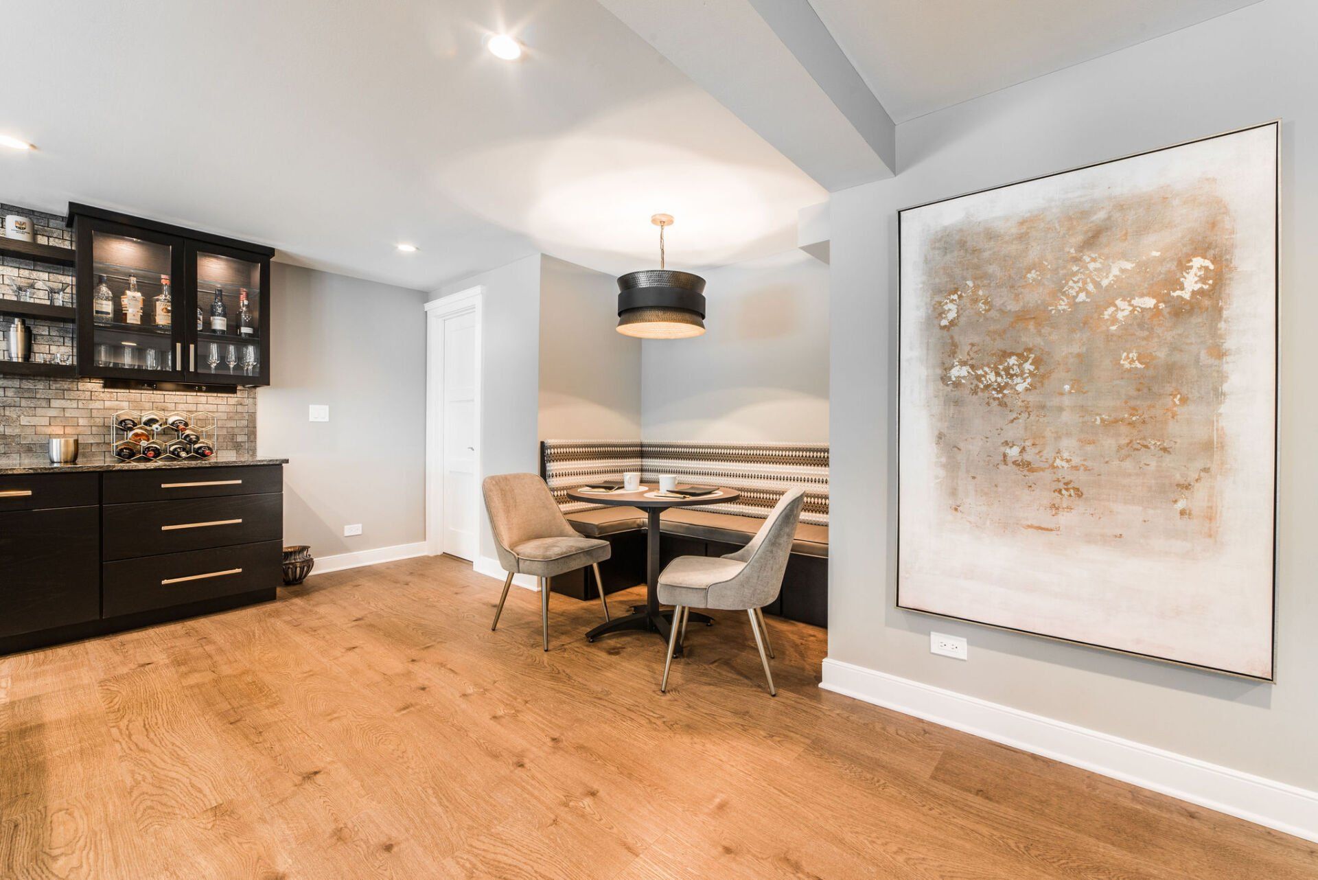 A dining room with a table and chairs and a painting on the wall.