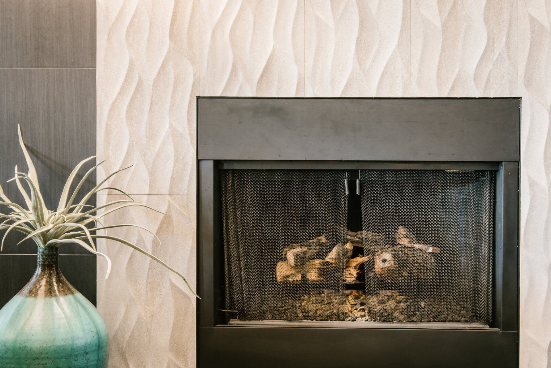 A fireplace with a plant in a vase next to it.