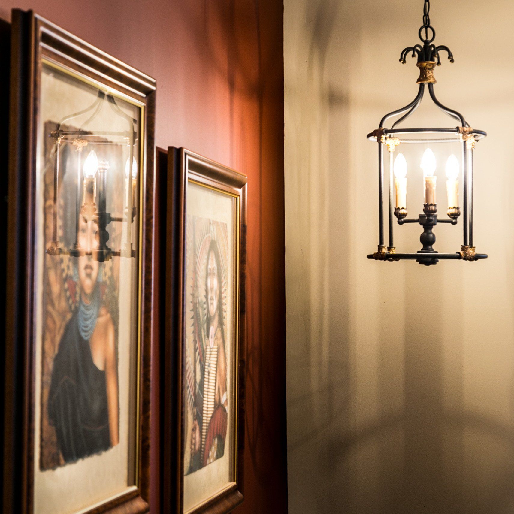 Two framed pictures are hanging on a wall next to a chandelier