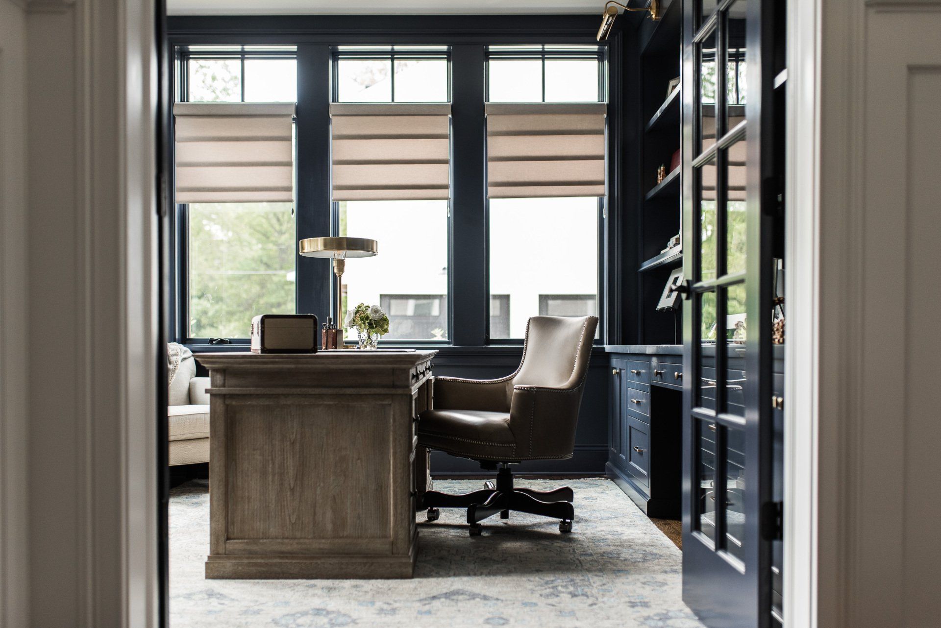 A home office with a desk , chair , lamp and bookshelves.