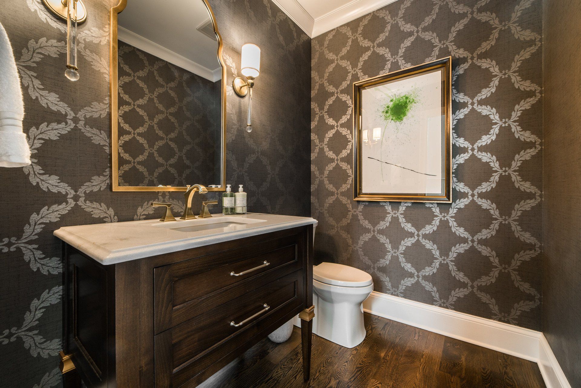 A bathroom with a sink , toilet , mirror and picture on the wall.