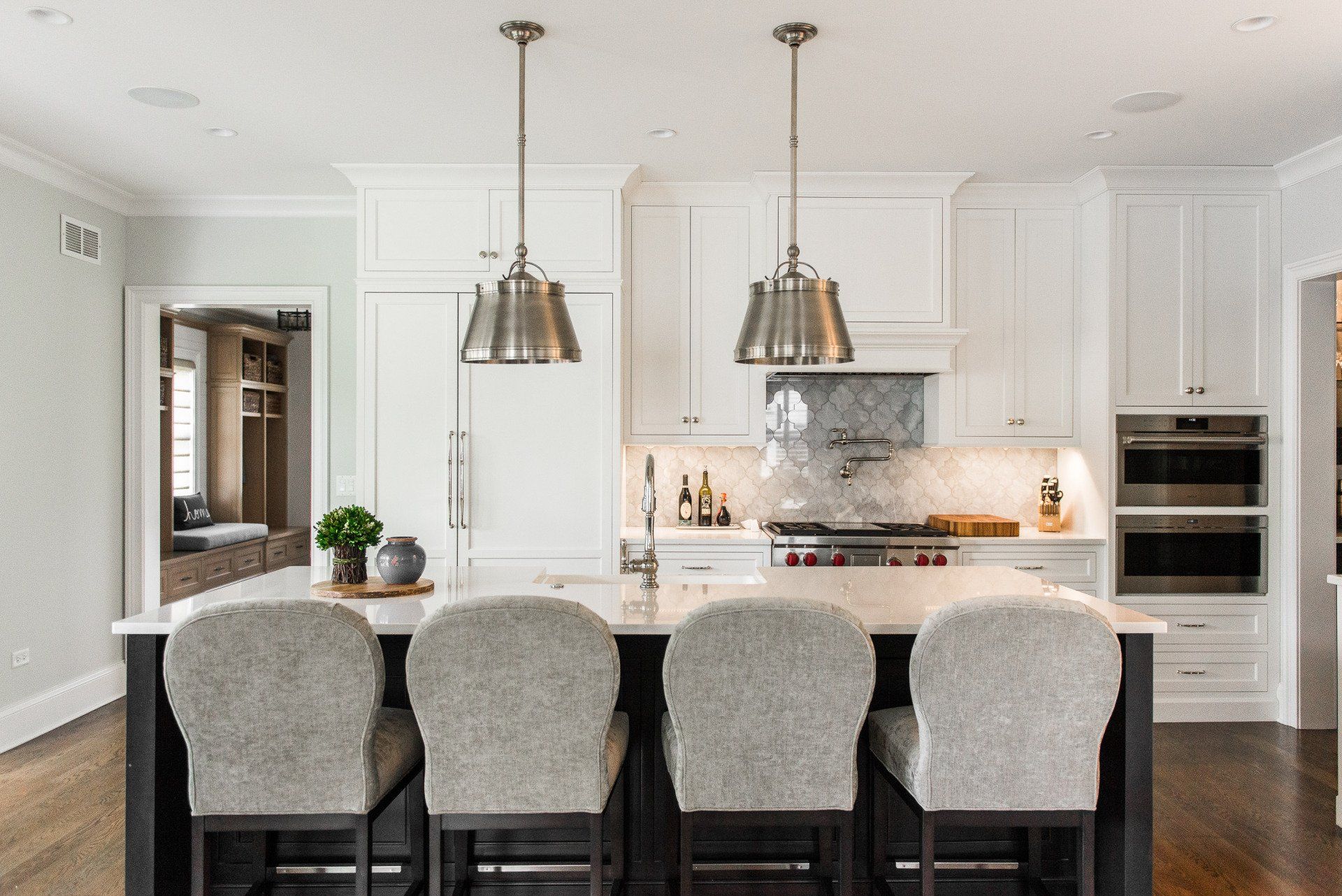 A kitchen with a large island and three chairs.