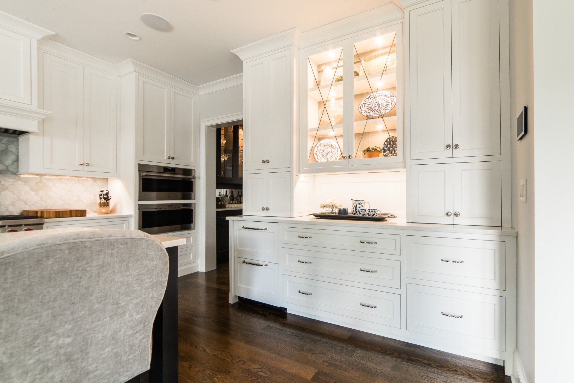 A kitchen with white cabinets and wooden floors.