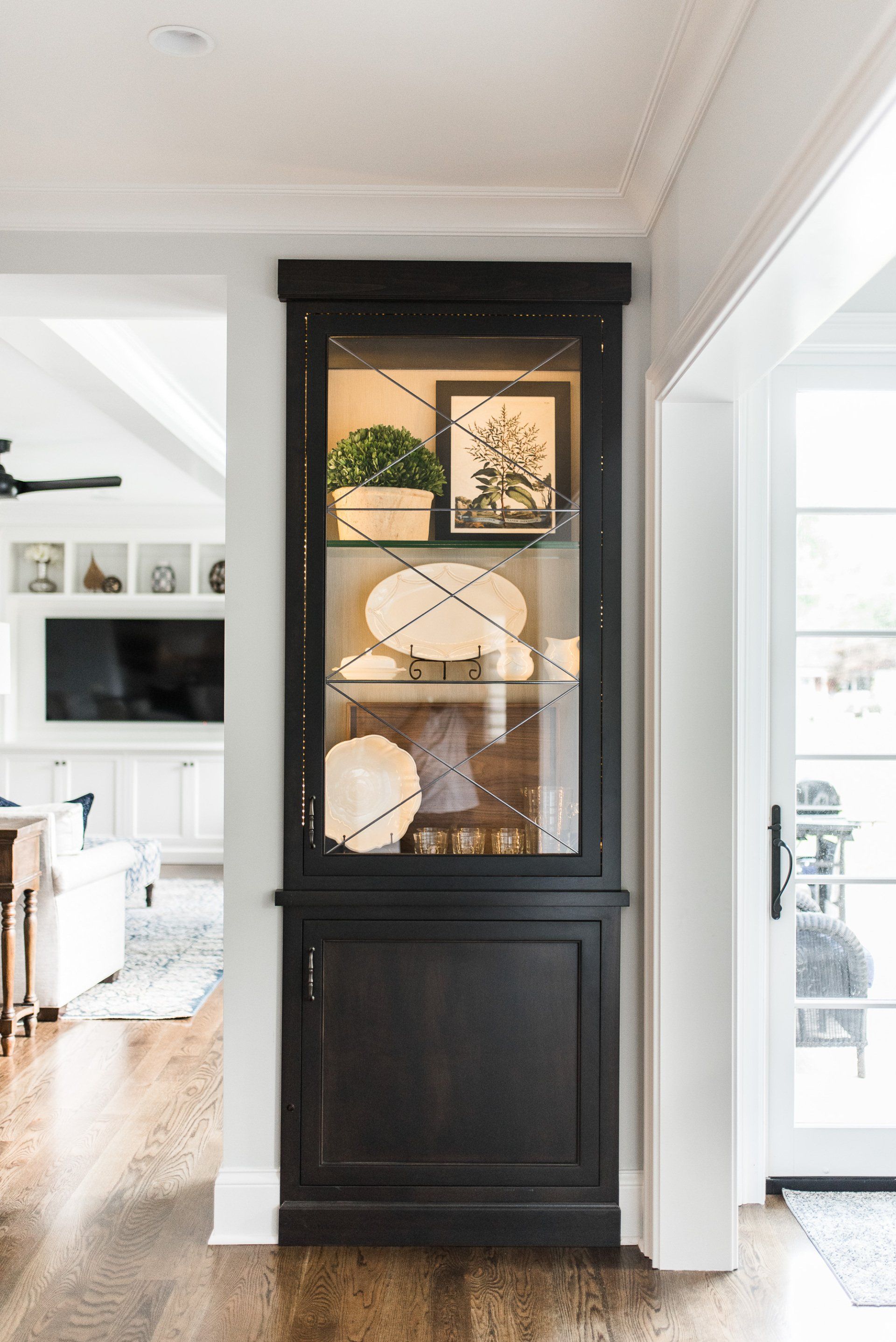 A black hutch with glass doors and shelves in a living room.