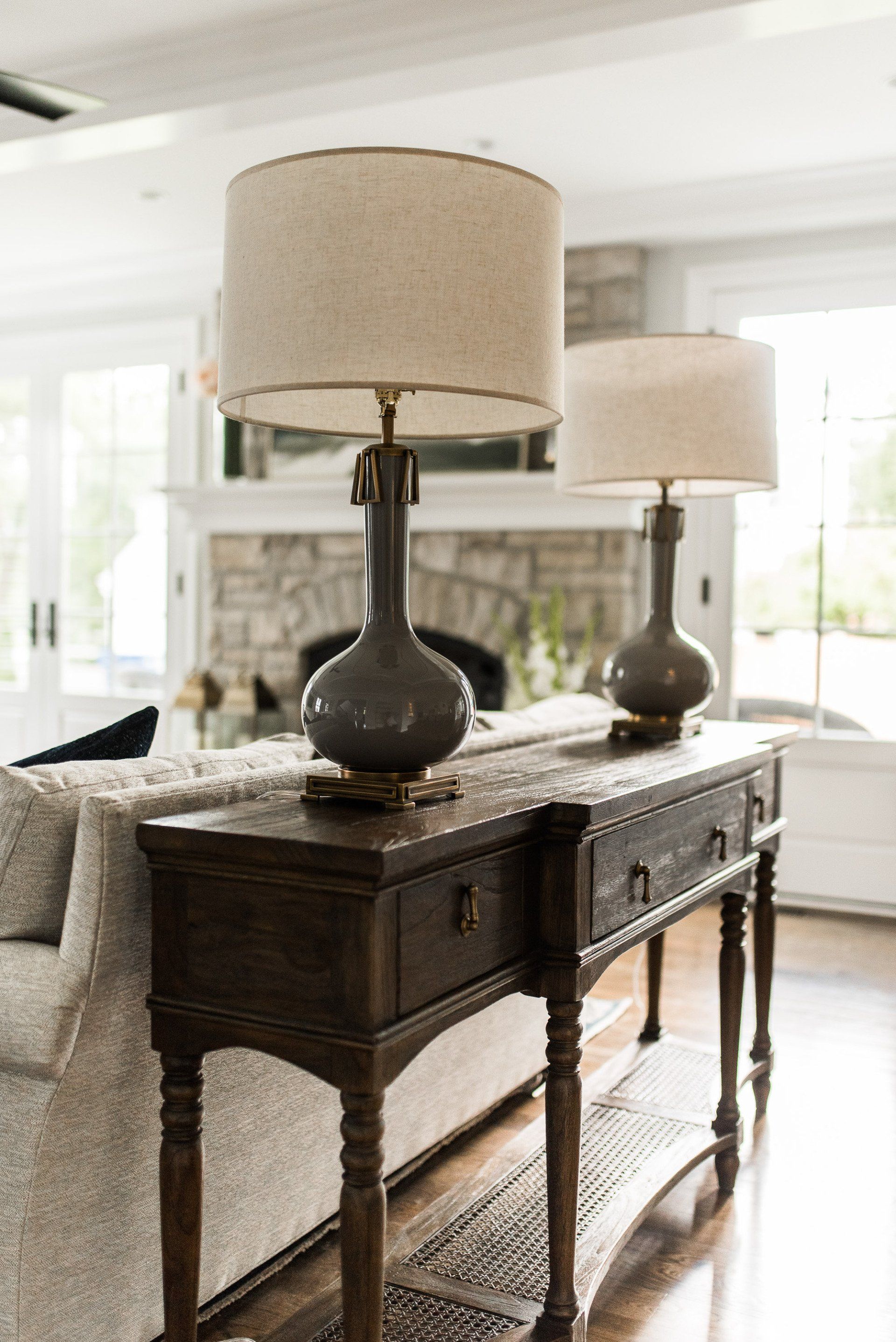 Two lamps are sitting on a wooden table in a living room next to a couch.
