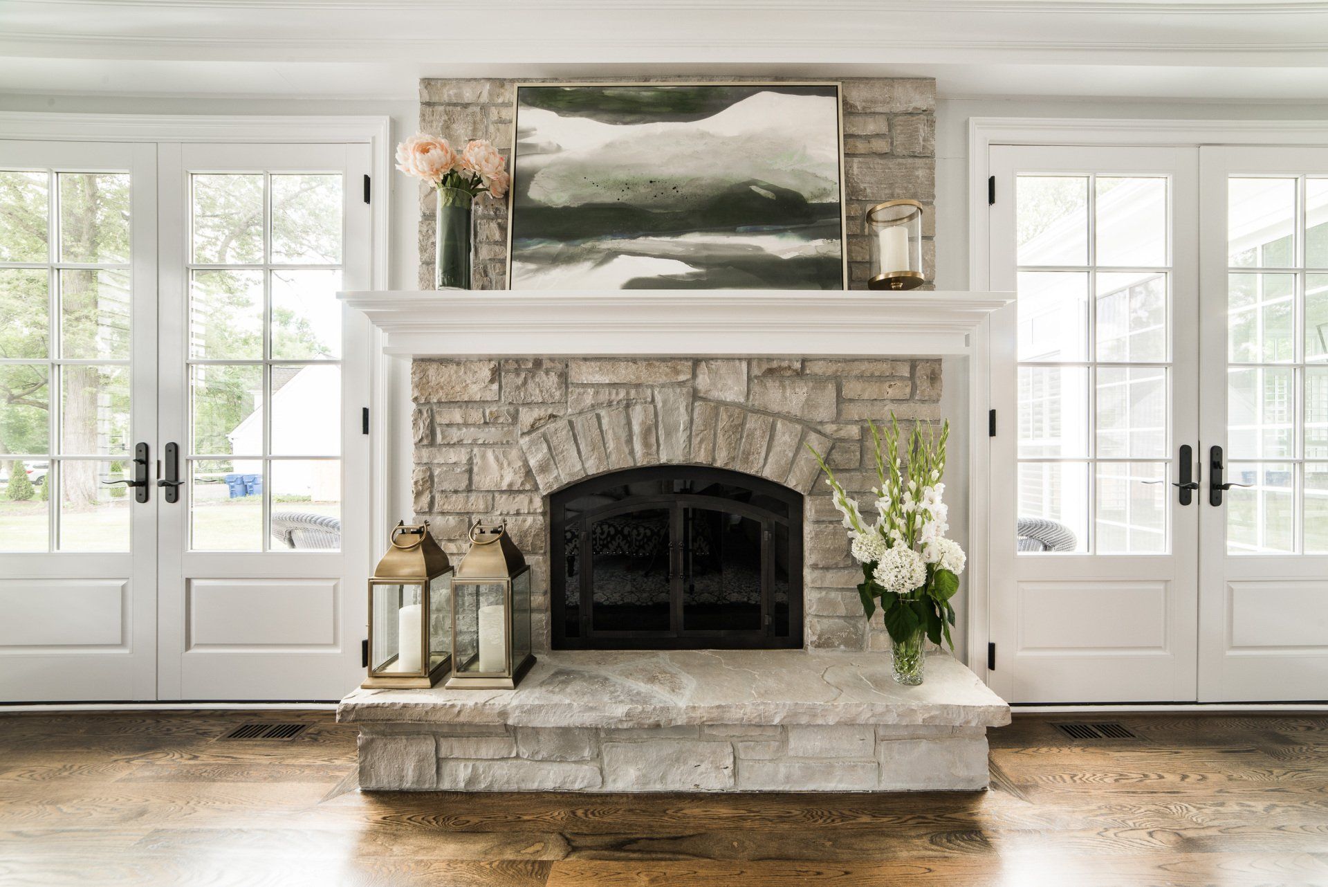 A living room with a stone fireplace and a painting on the wall.