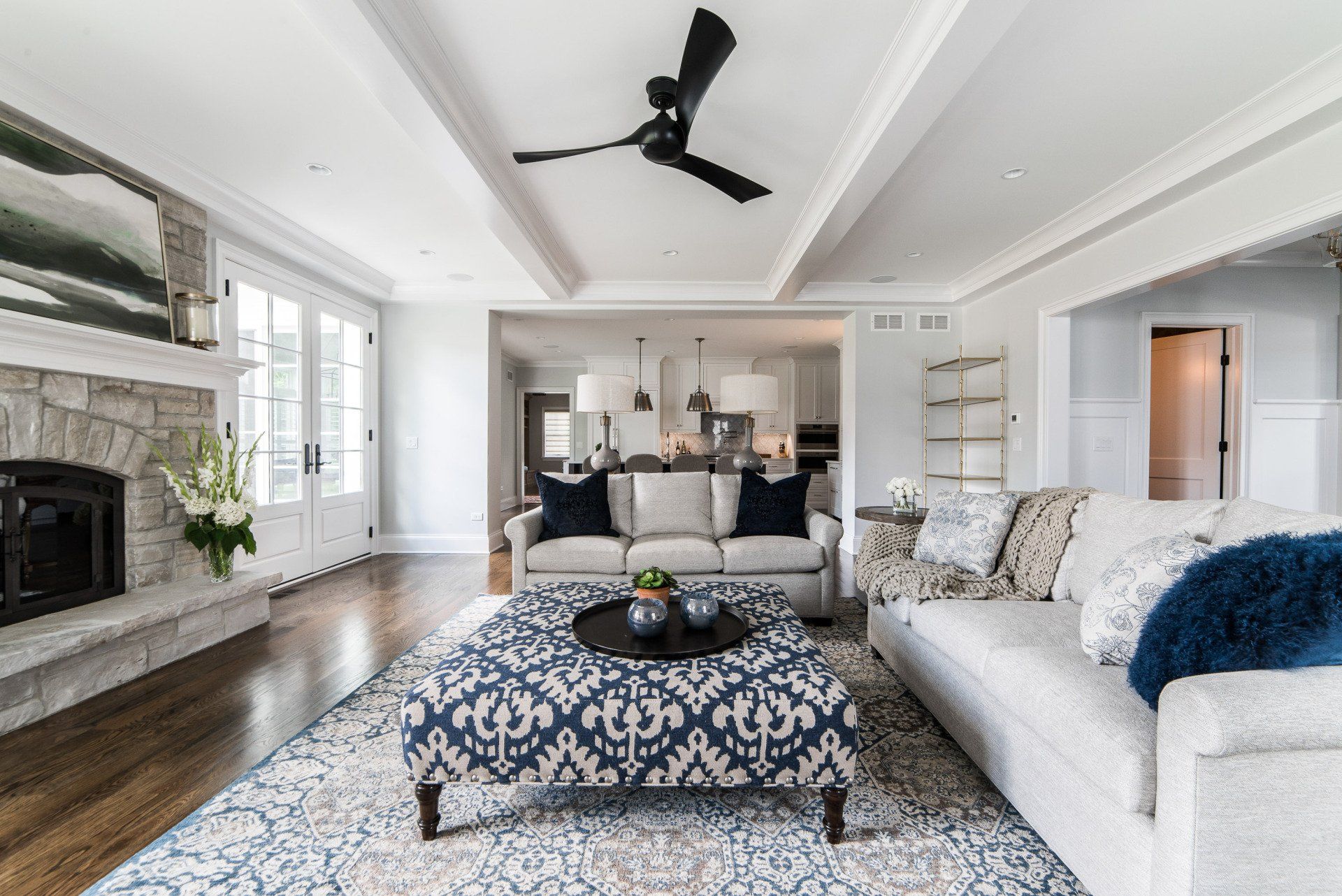 A living room with a couch , coffee table , fireplace and ceiling fan.