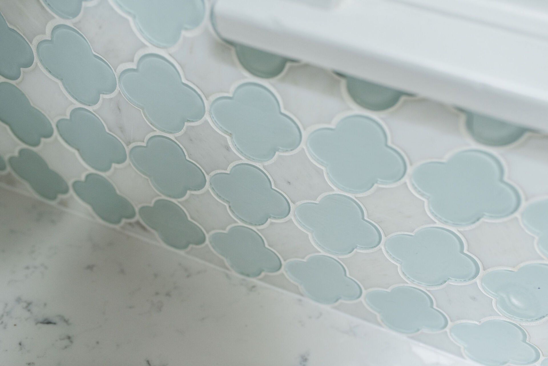 A close up of a bathroom sink with blue and white tiles.