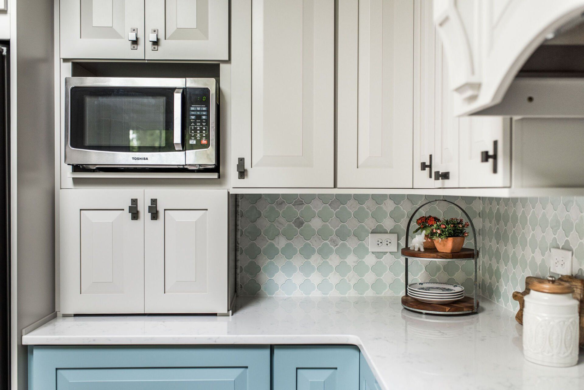 A kitchen with white cabinets and blue counter tops and a microwave.