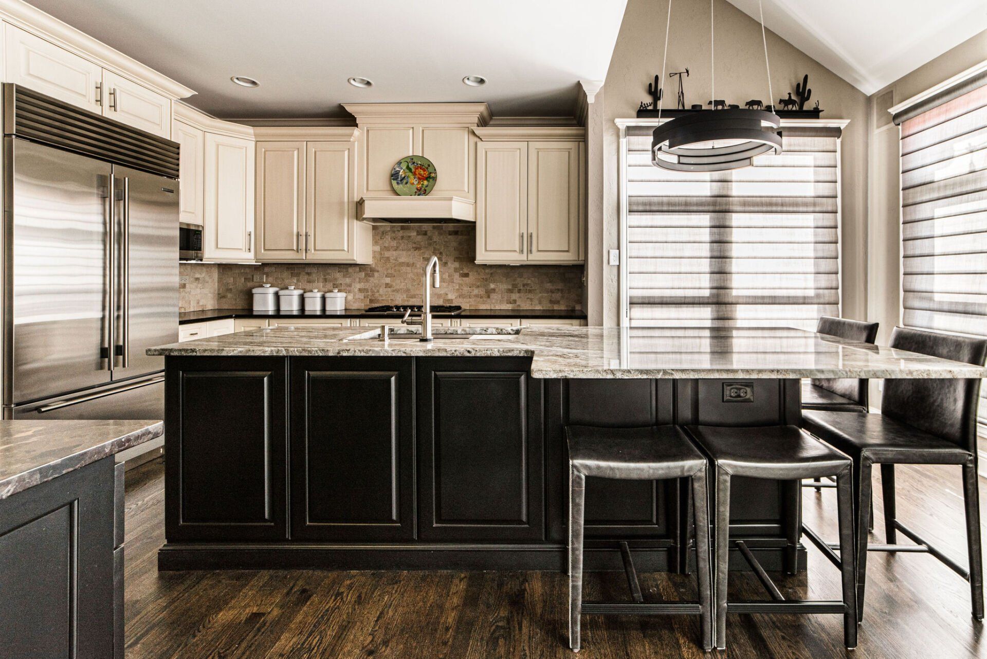 A kitchen with black cabinets , granite counter tops , stainless steel appliances and a large island.