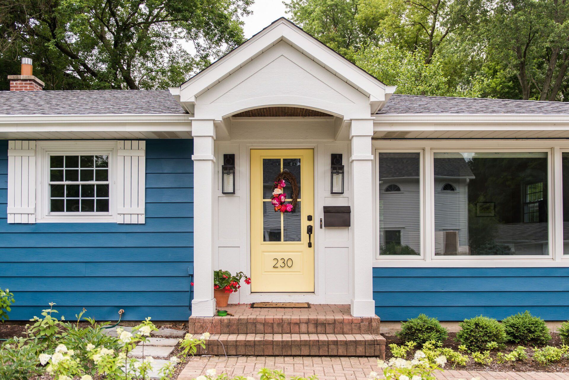 The front of a blue and white house with a yellow door.