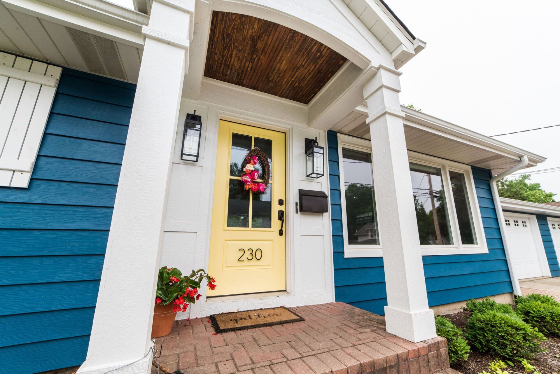 A blue and white house with a yellow door and a porch.