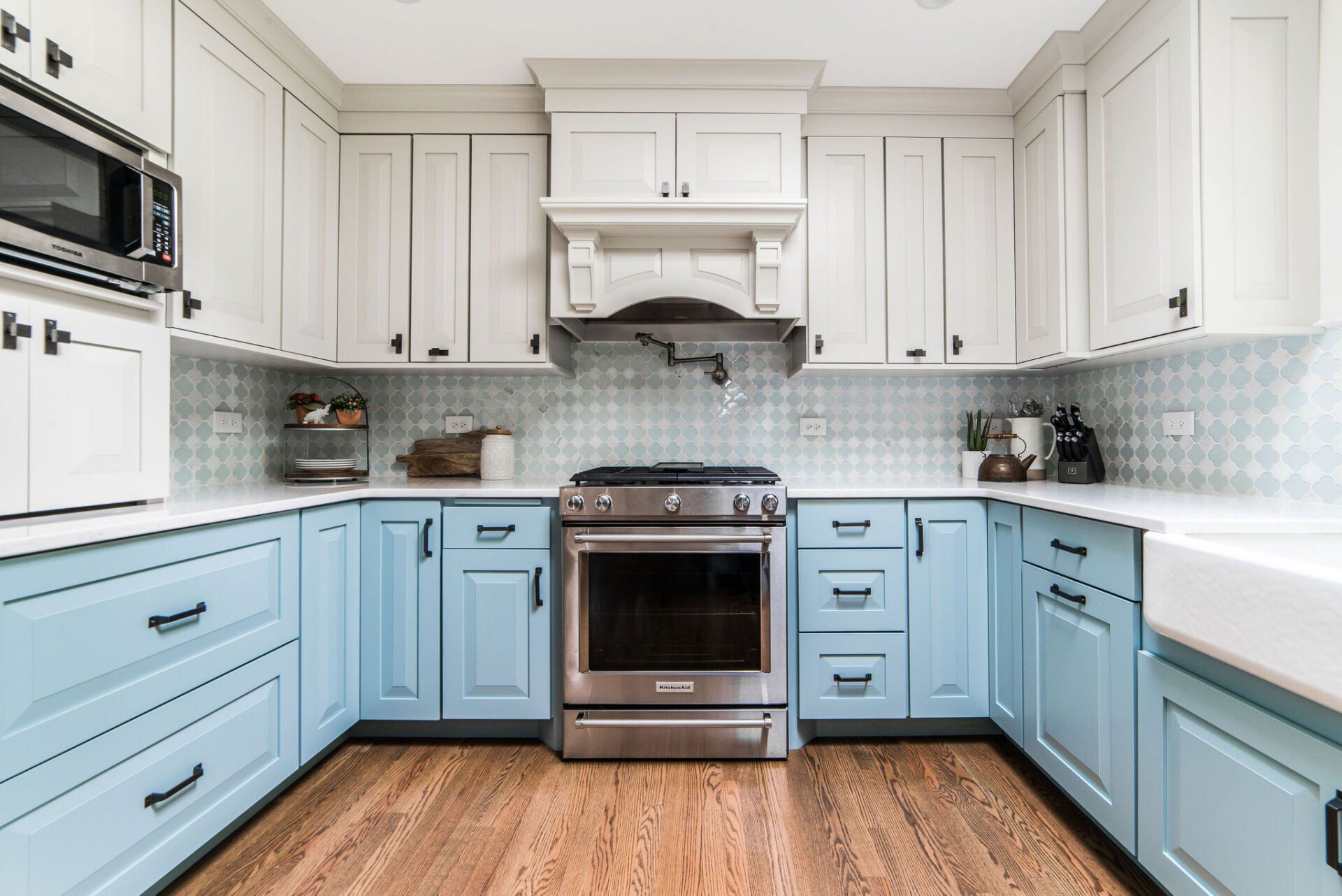 A kitchen with blue cabinets and white counter tops and a stove.