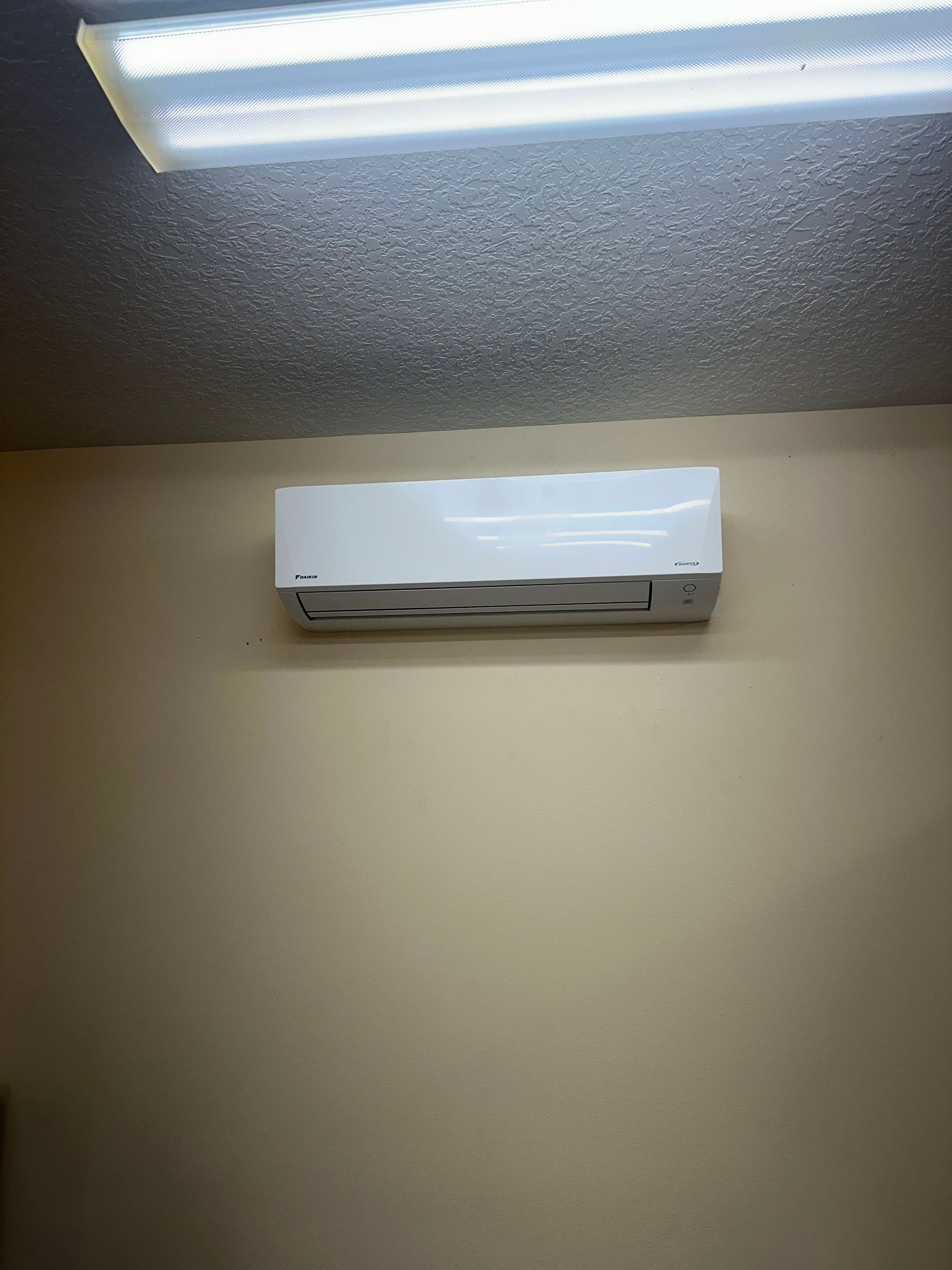 a white air conditioner is hanging from the ceiling in a room .