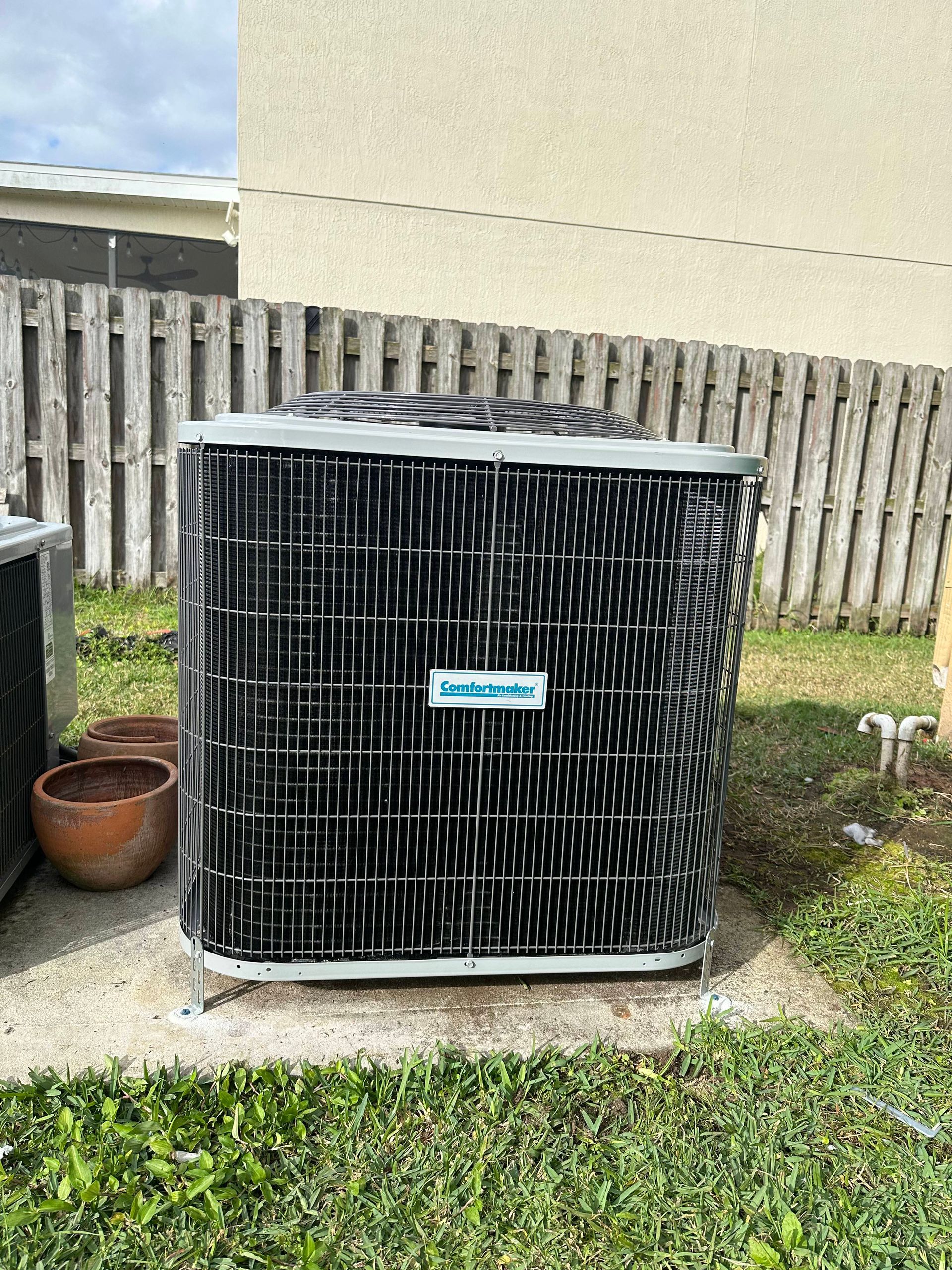 a large air conditioner is sitting in the grass in front of a house .