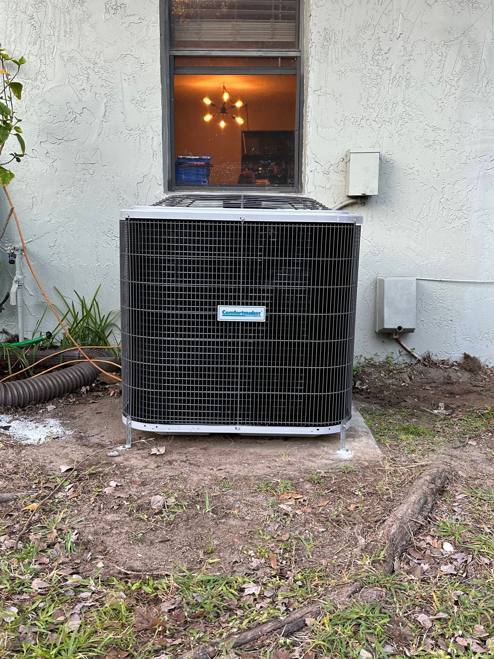 a large air conditioner is sitting outside of a house next to a window .