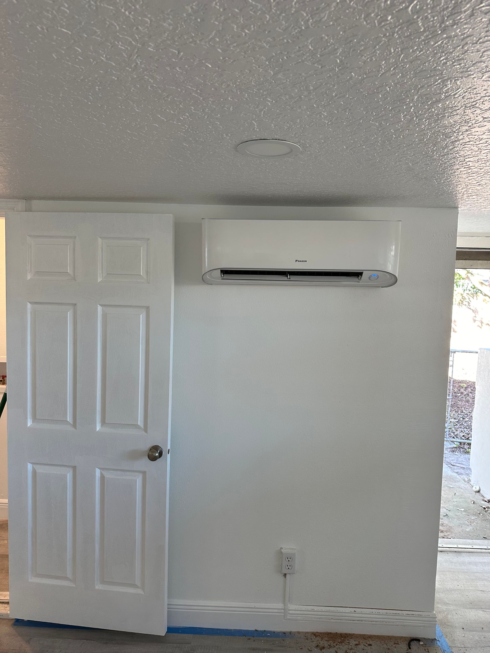 a room with a door and a wall mounted air conditioner .