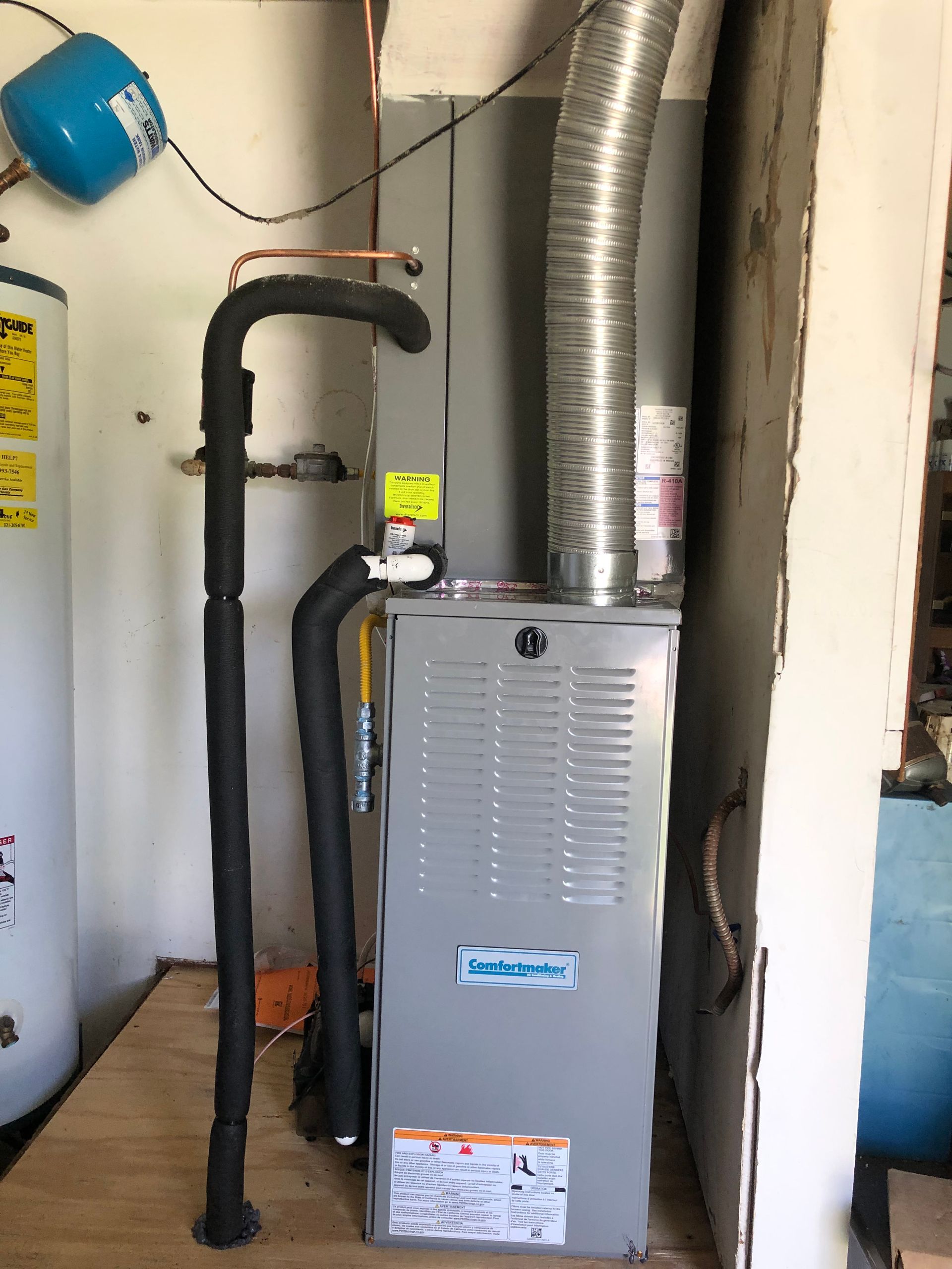 a gas heater is sitting next to a water heater in a room .