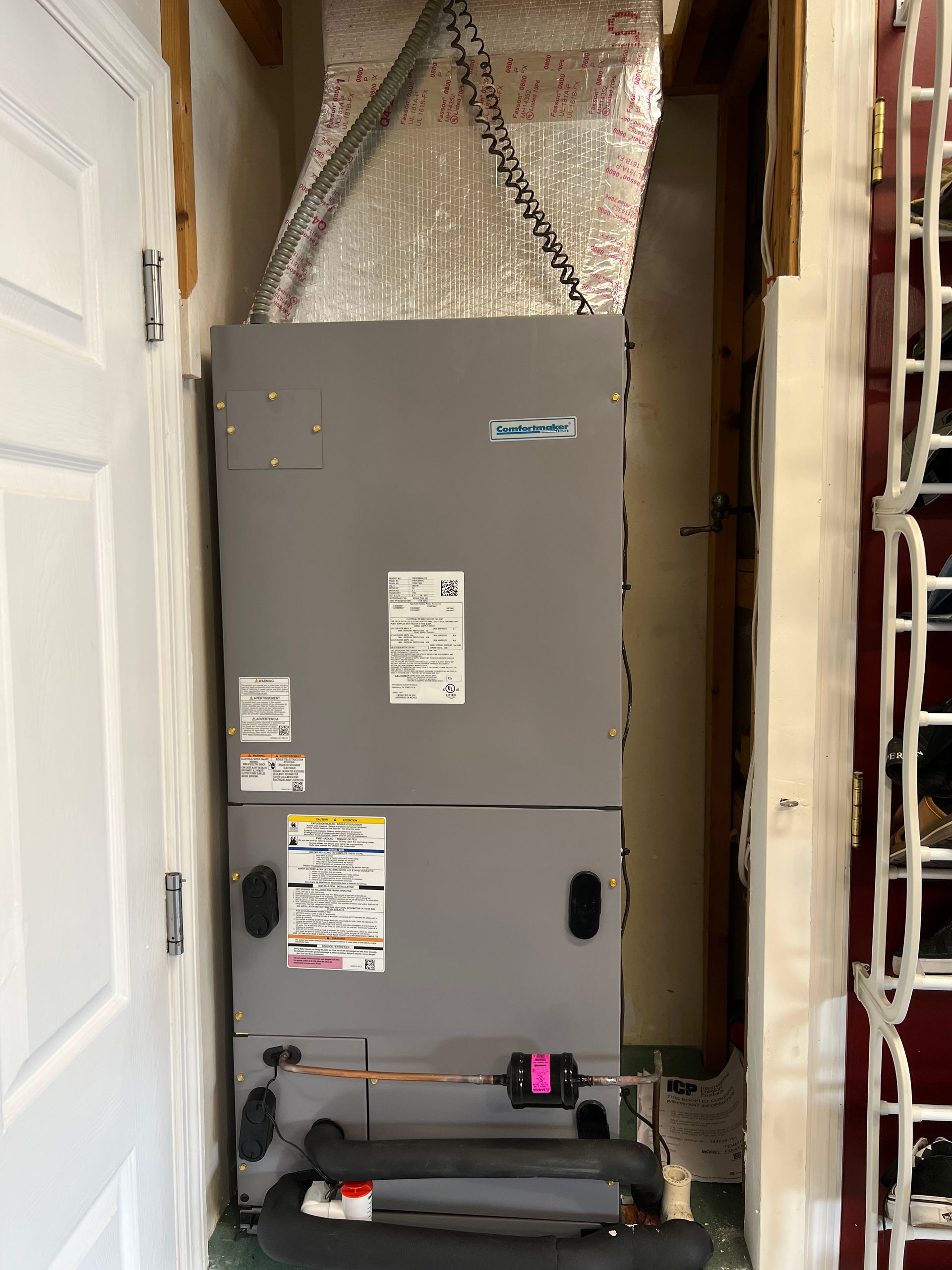 a gray air conditioner is sitting in a closet next to a door .