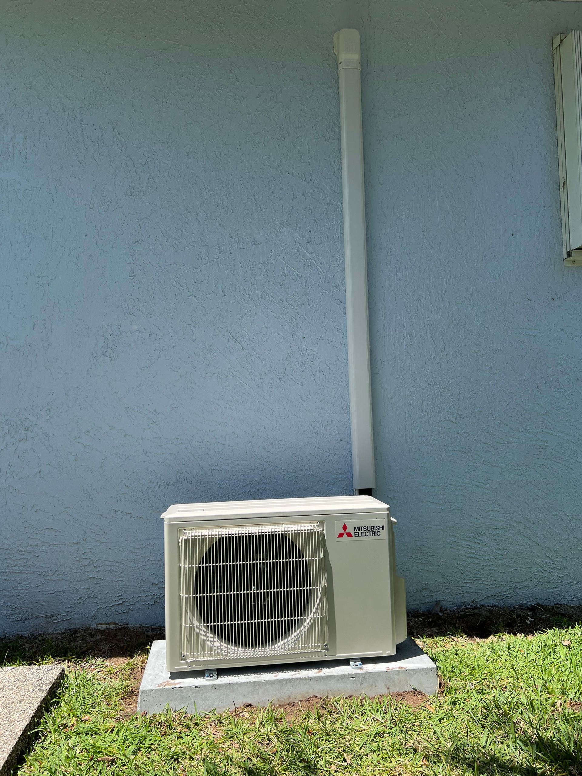 a white air conditioner is mounted on the side of a building .