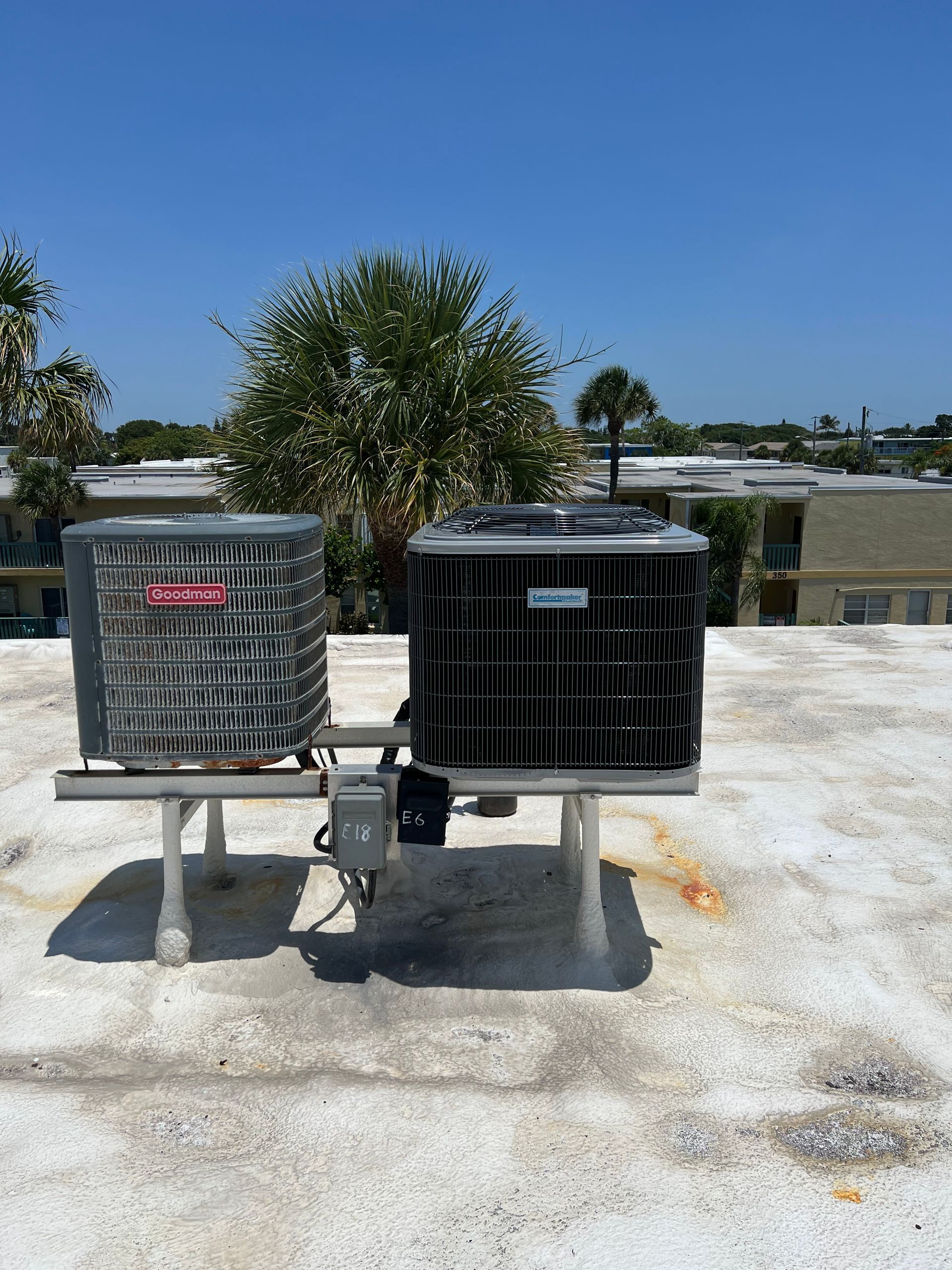 two air conditioners are sitting on top of a white roof .